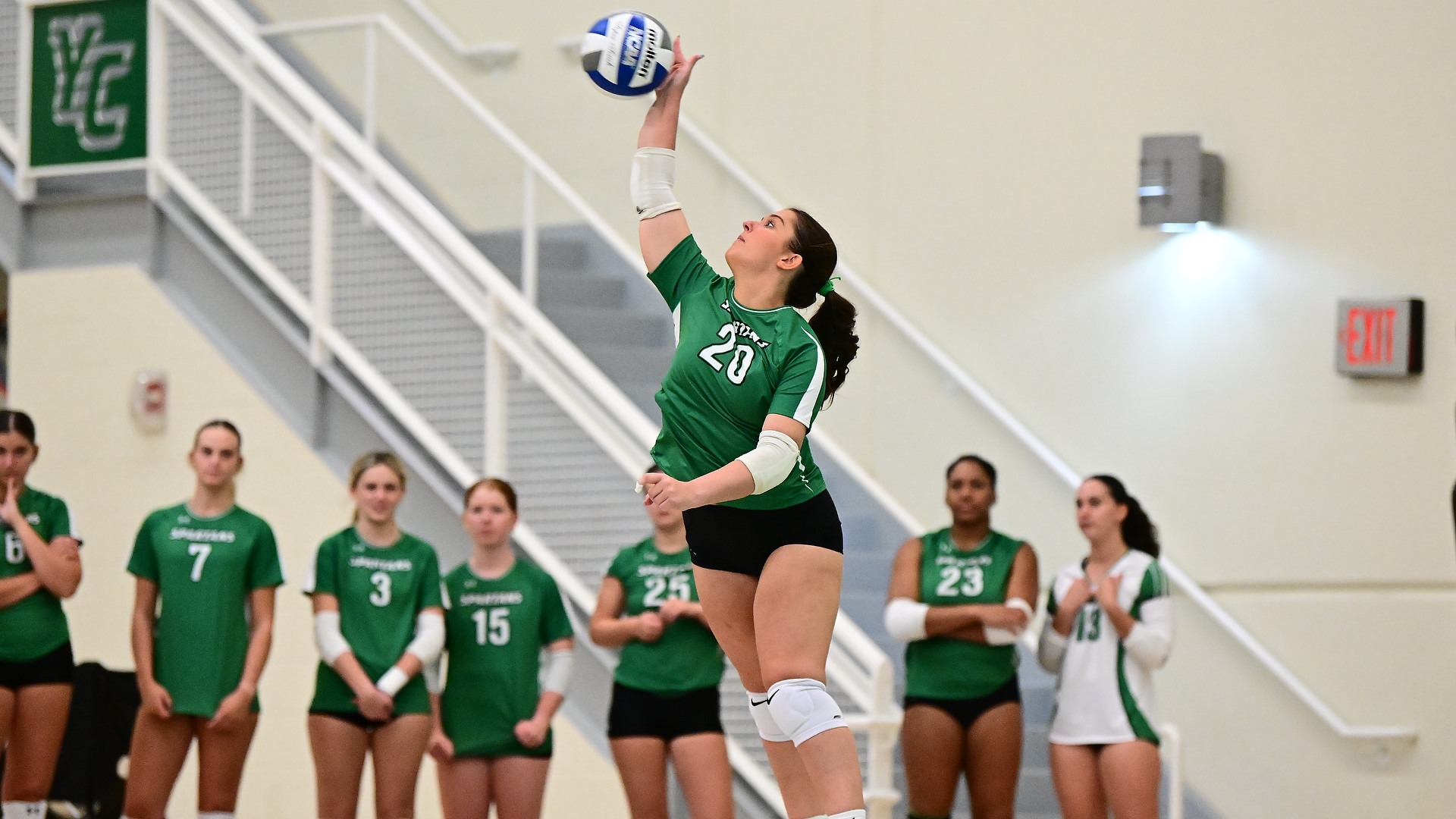 female volleyball player serves ball