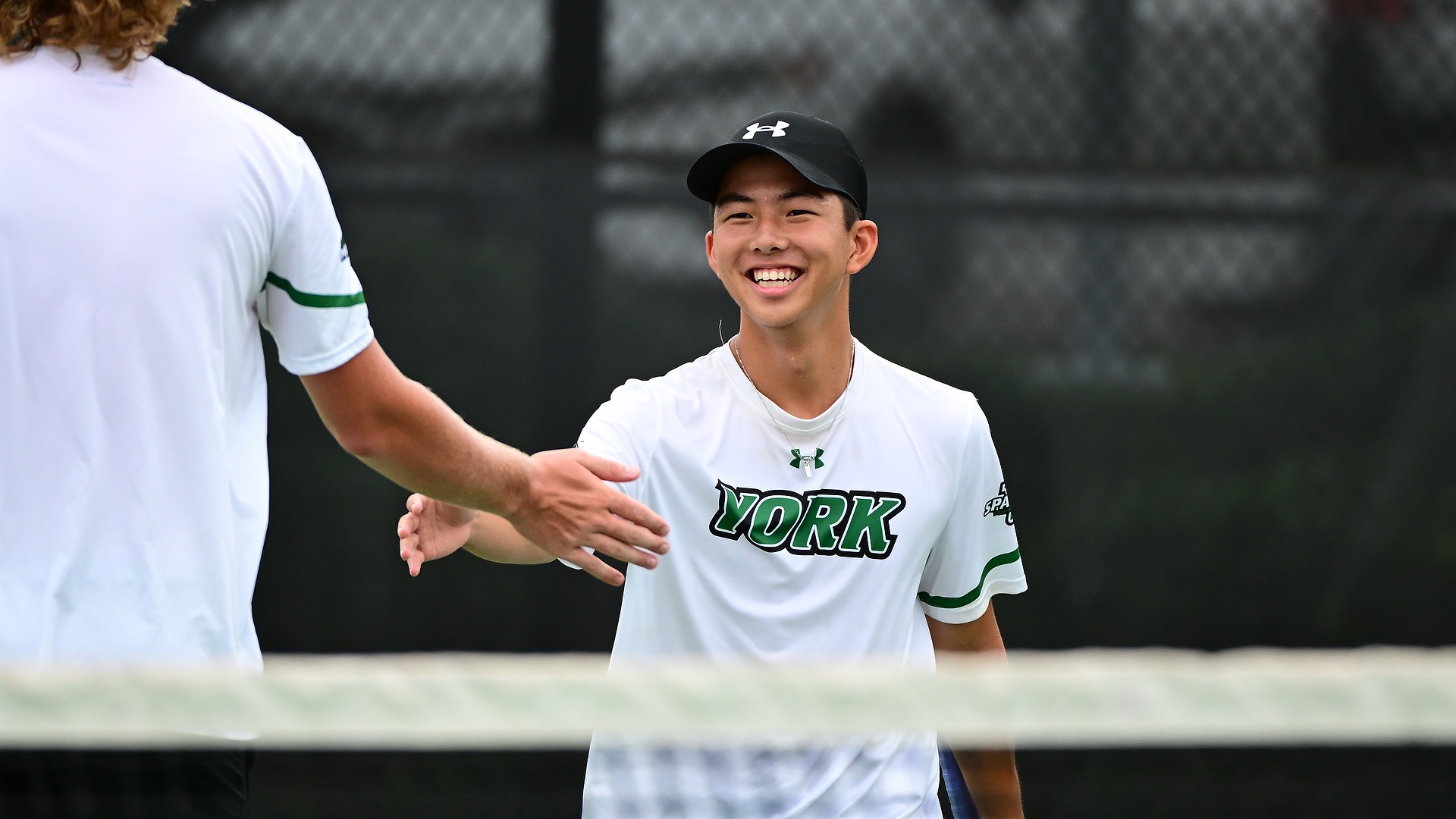 Male tennis player celebrates with teammate 