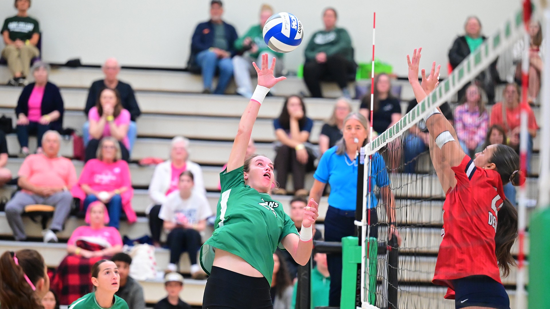 female volleyball player spikes ball over. net