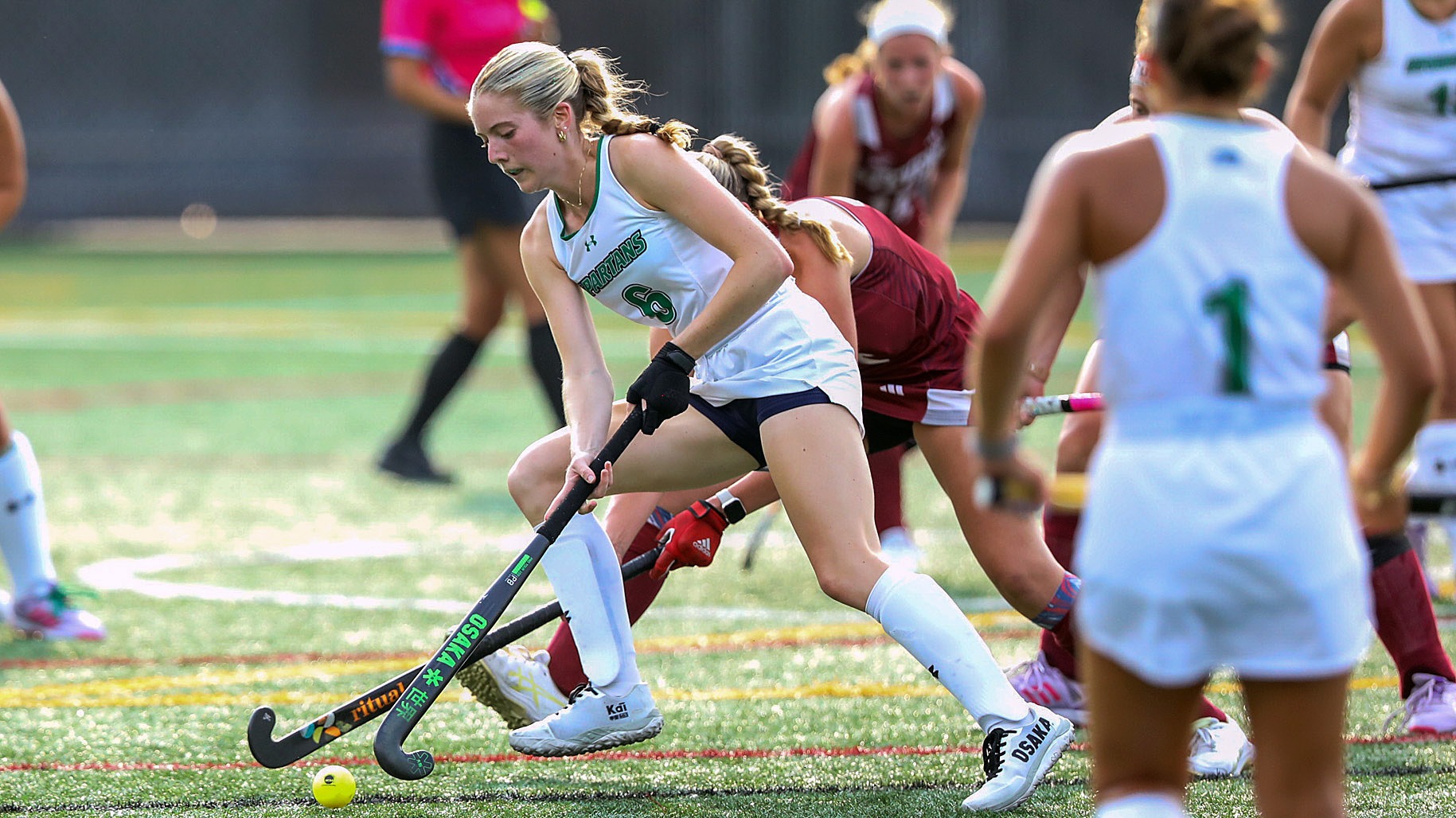 female field hockey player dribbles towards the goal