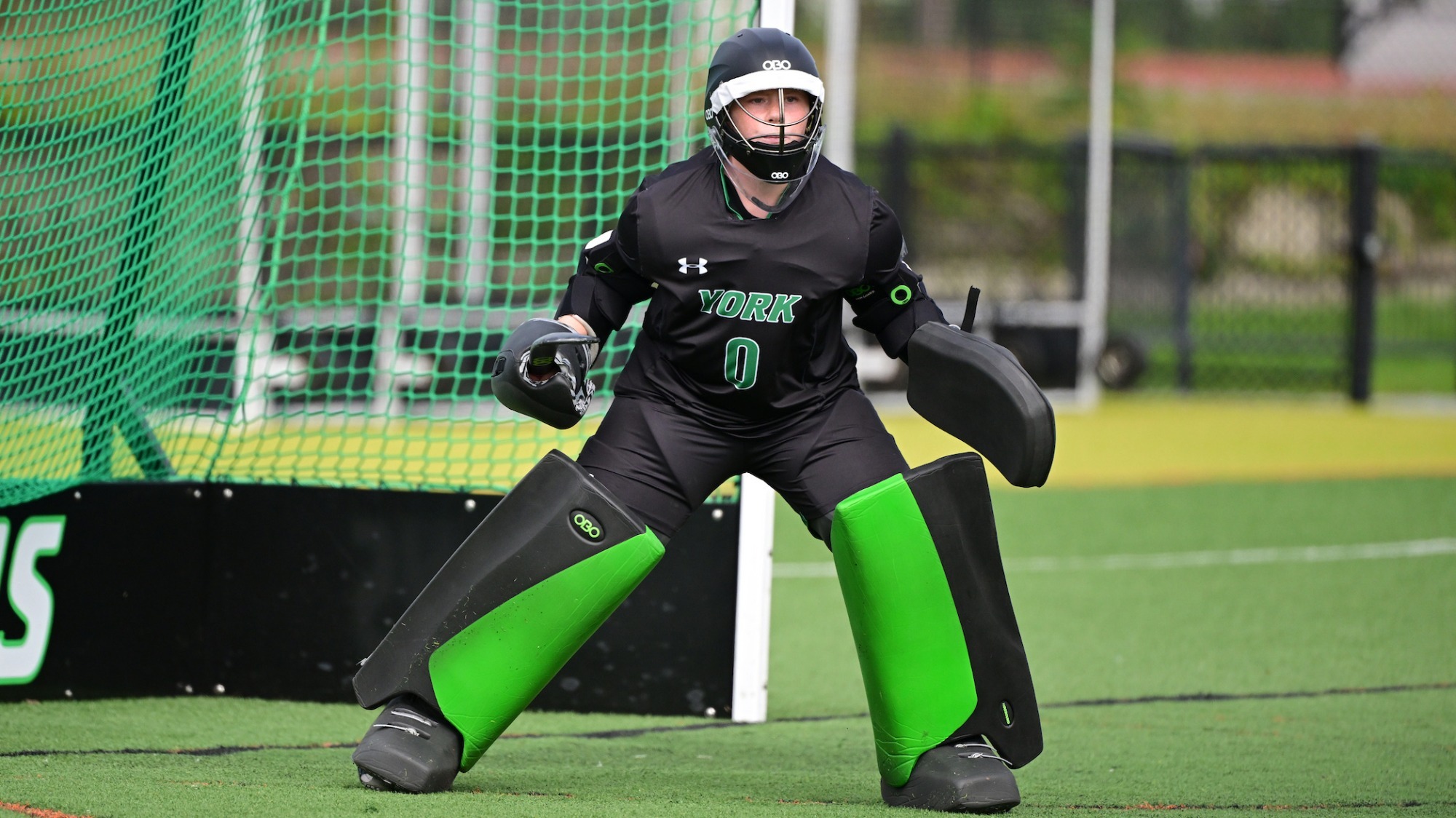 female field hockey goalie prepares to make a save