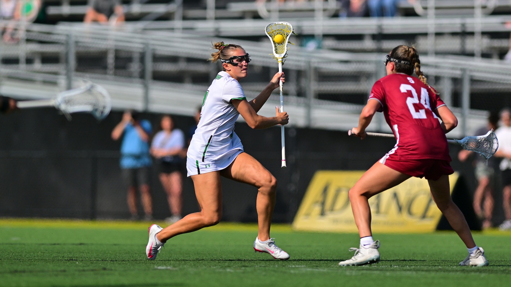 female lacrosse player maneuvers past defender