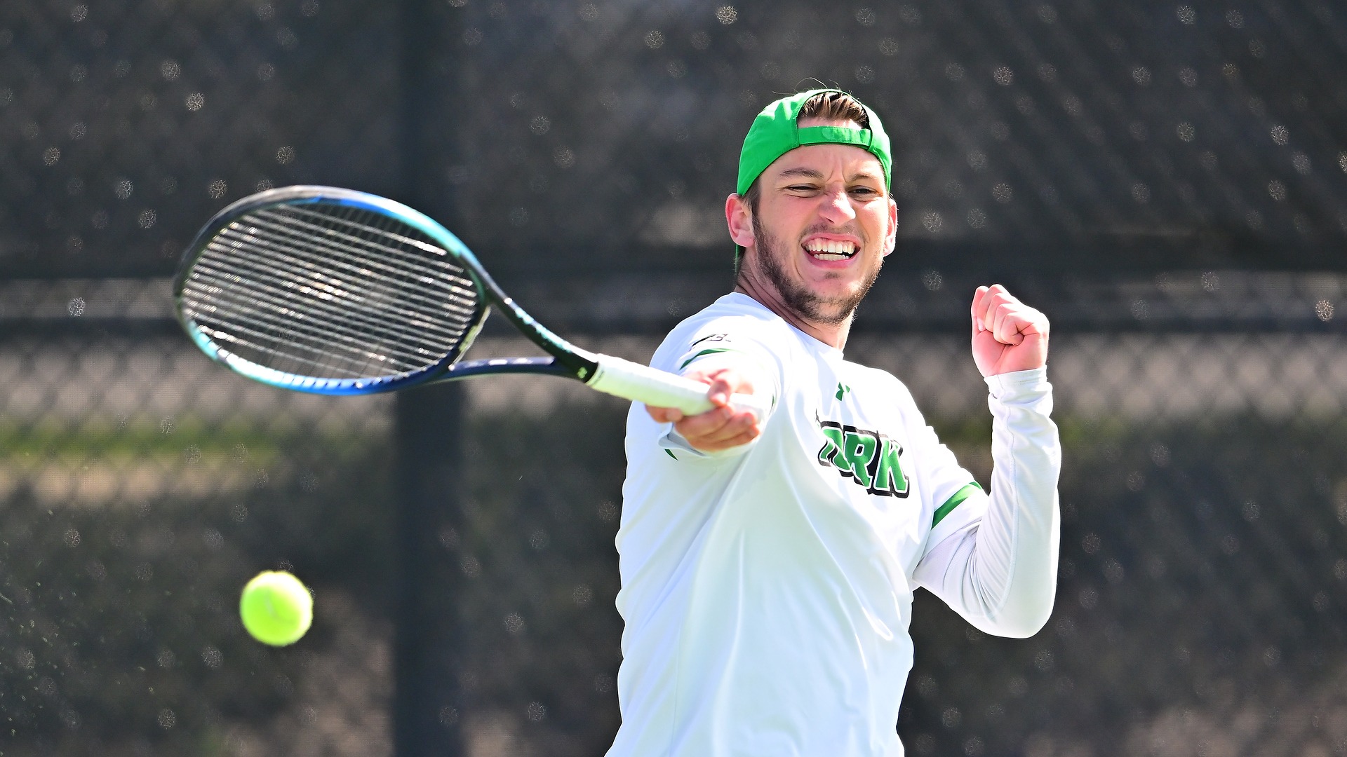 male tennis player in green hat hits ball