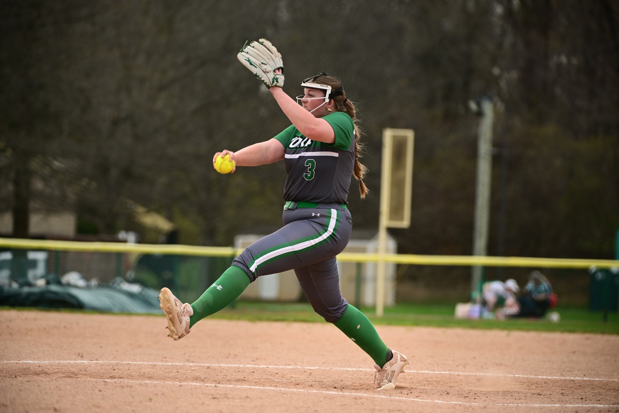 female in grey uniform pitching a softball