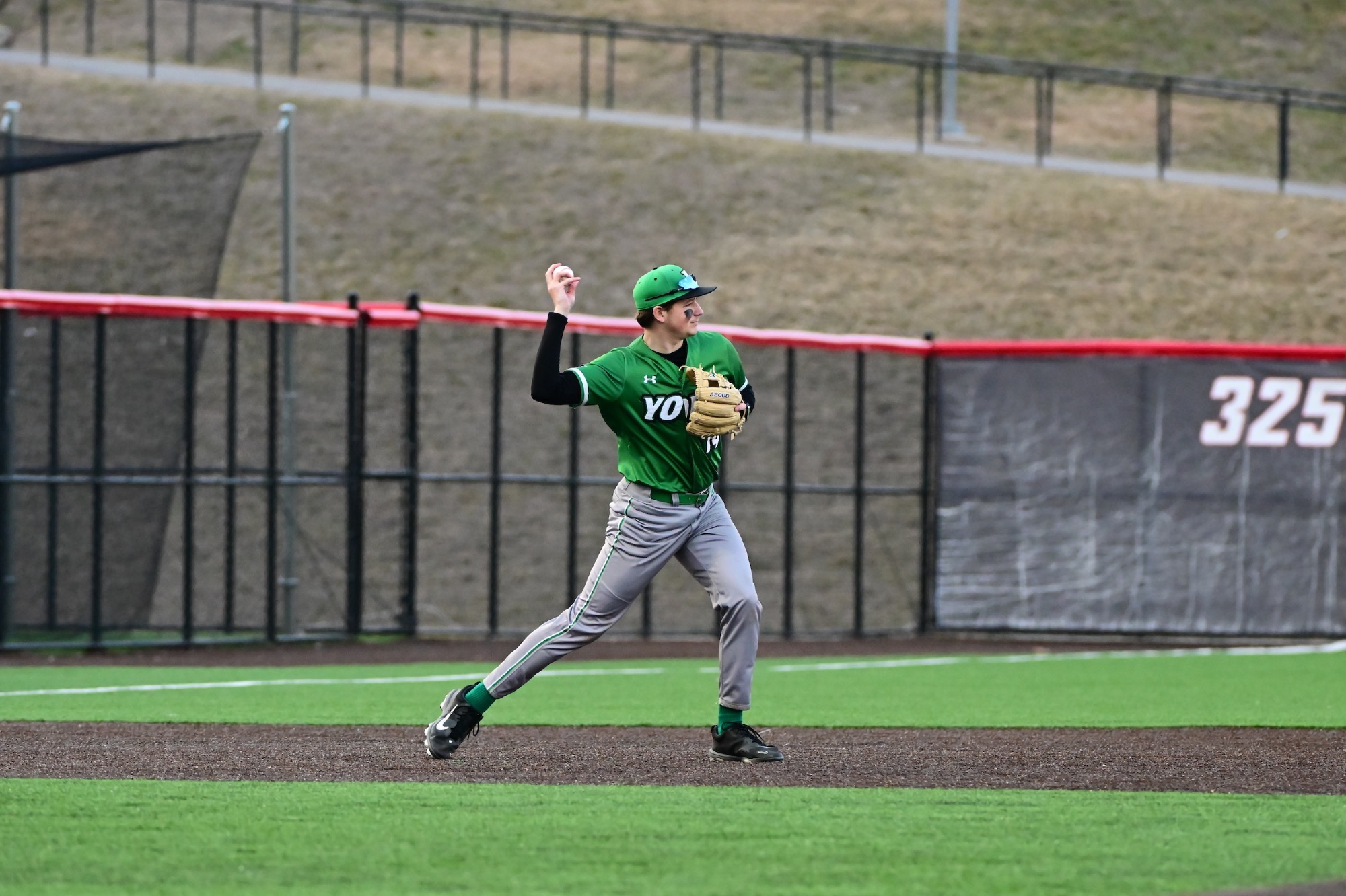 male in green uniform throwing baseball