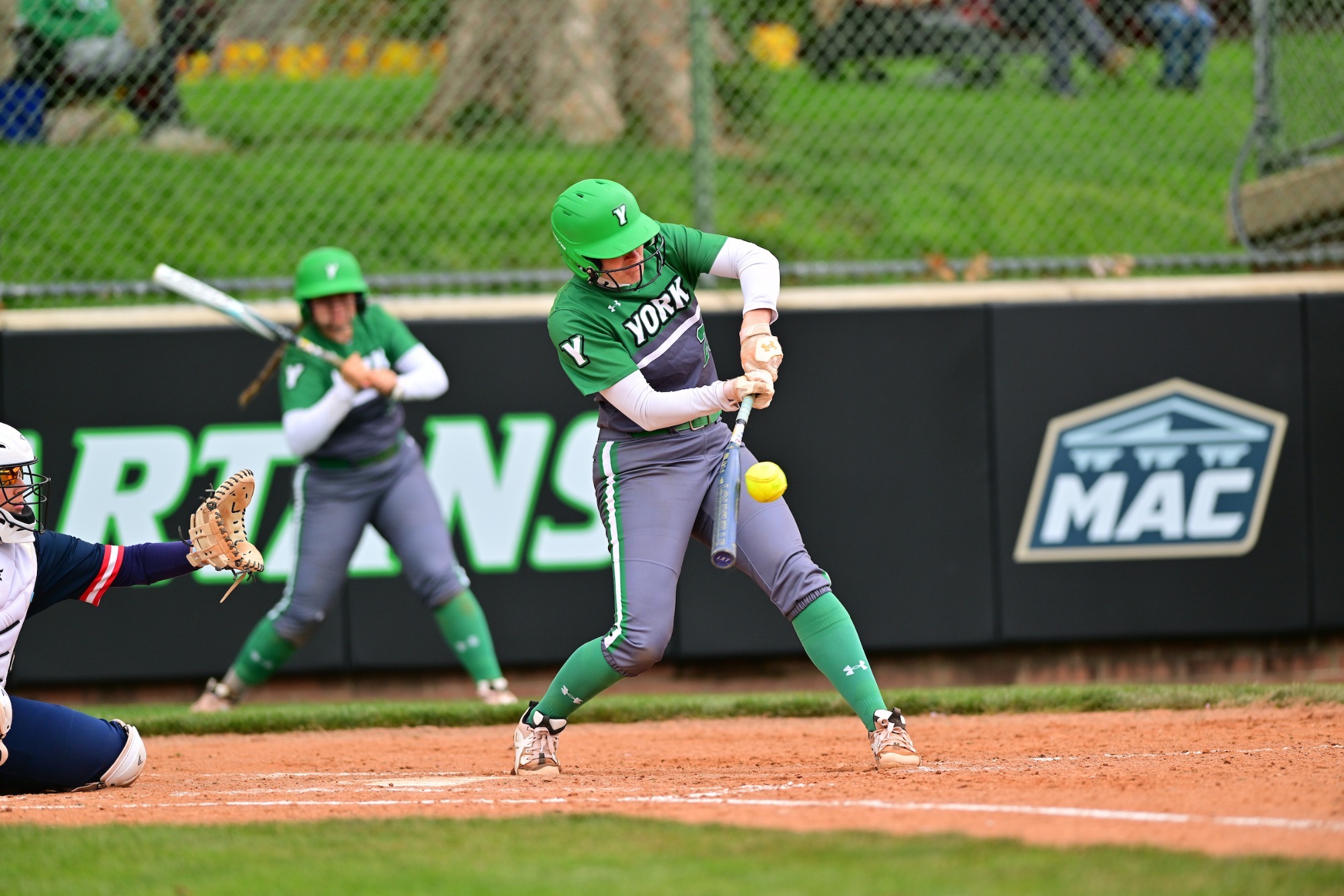 female in grey uniform swinging softball bat