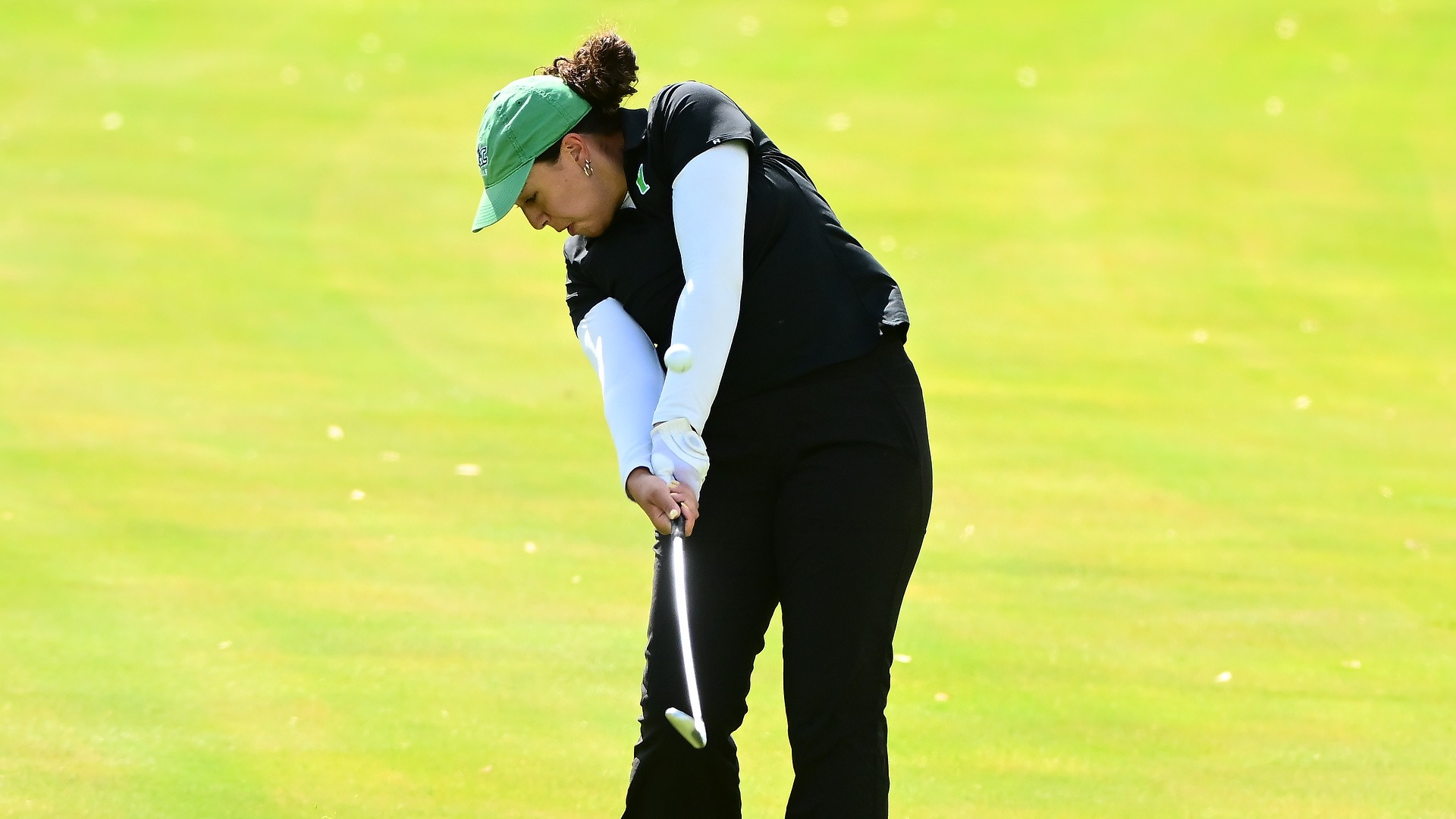 female golfer in black shirt hits wedge shot