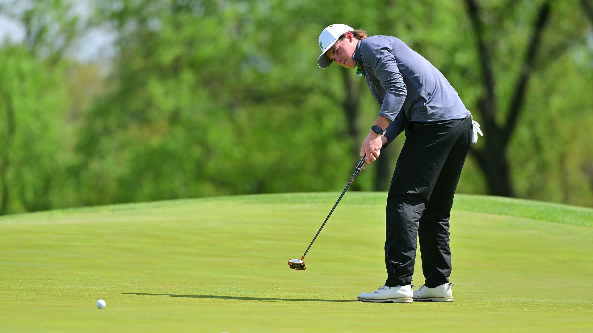 male golfer puts ball towards the hole