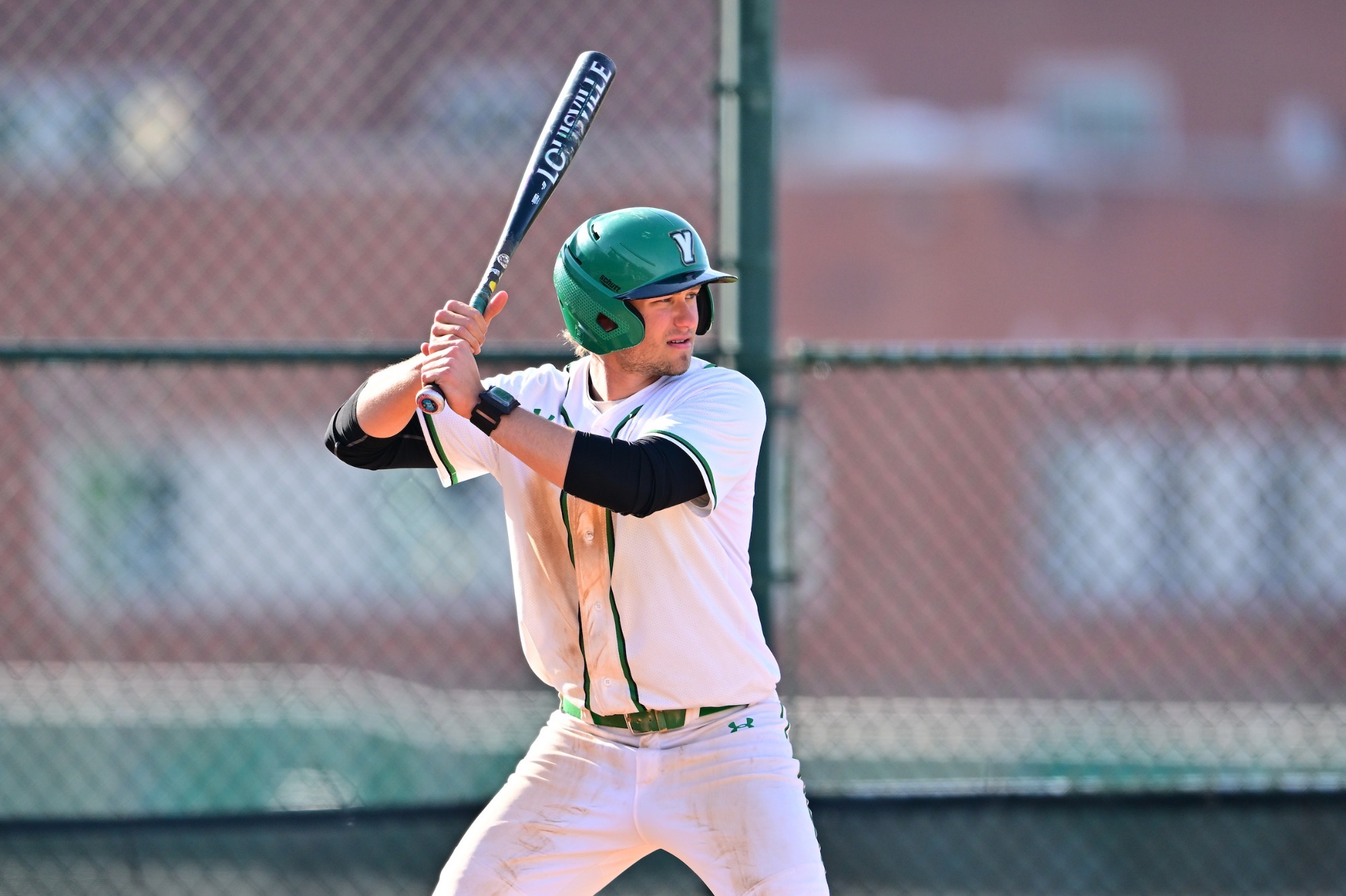 Male in white uniform holding baseball bat