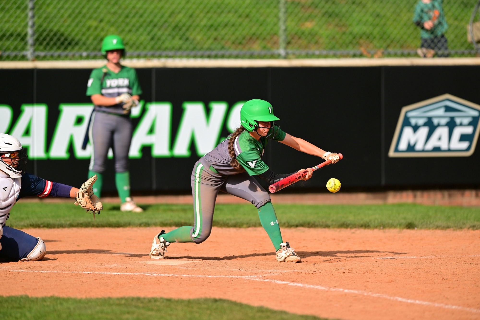 Female in grey uniform bunting a softball
