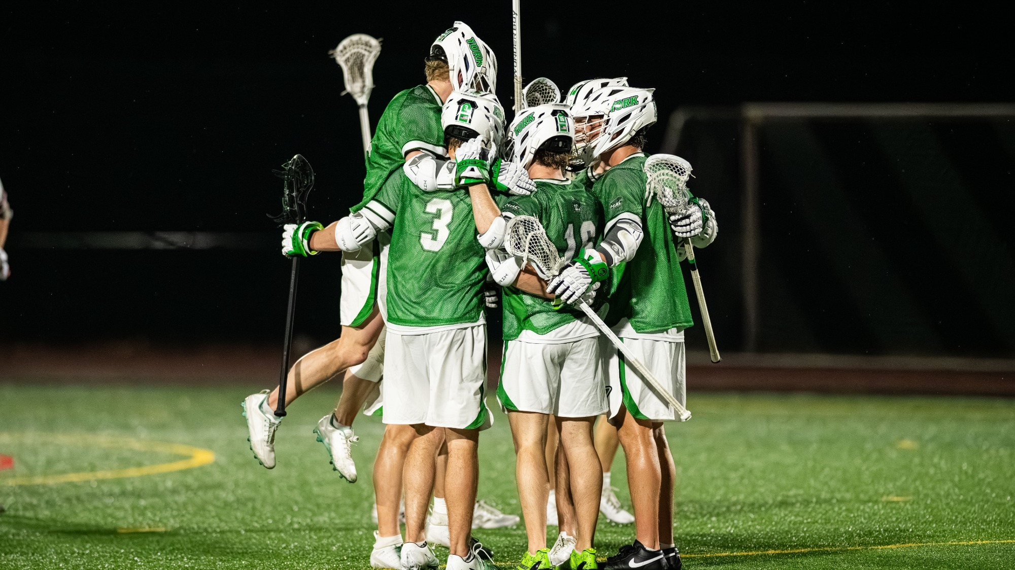 men's lacrosse players huddle up after a goal