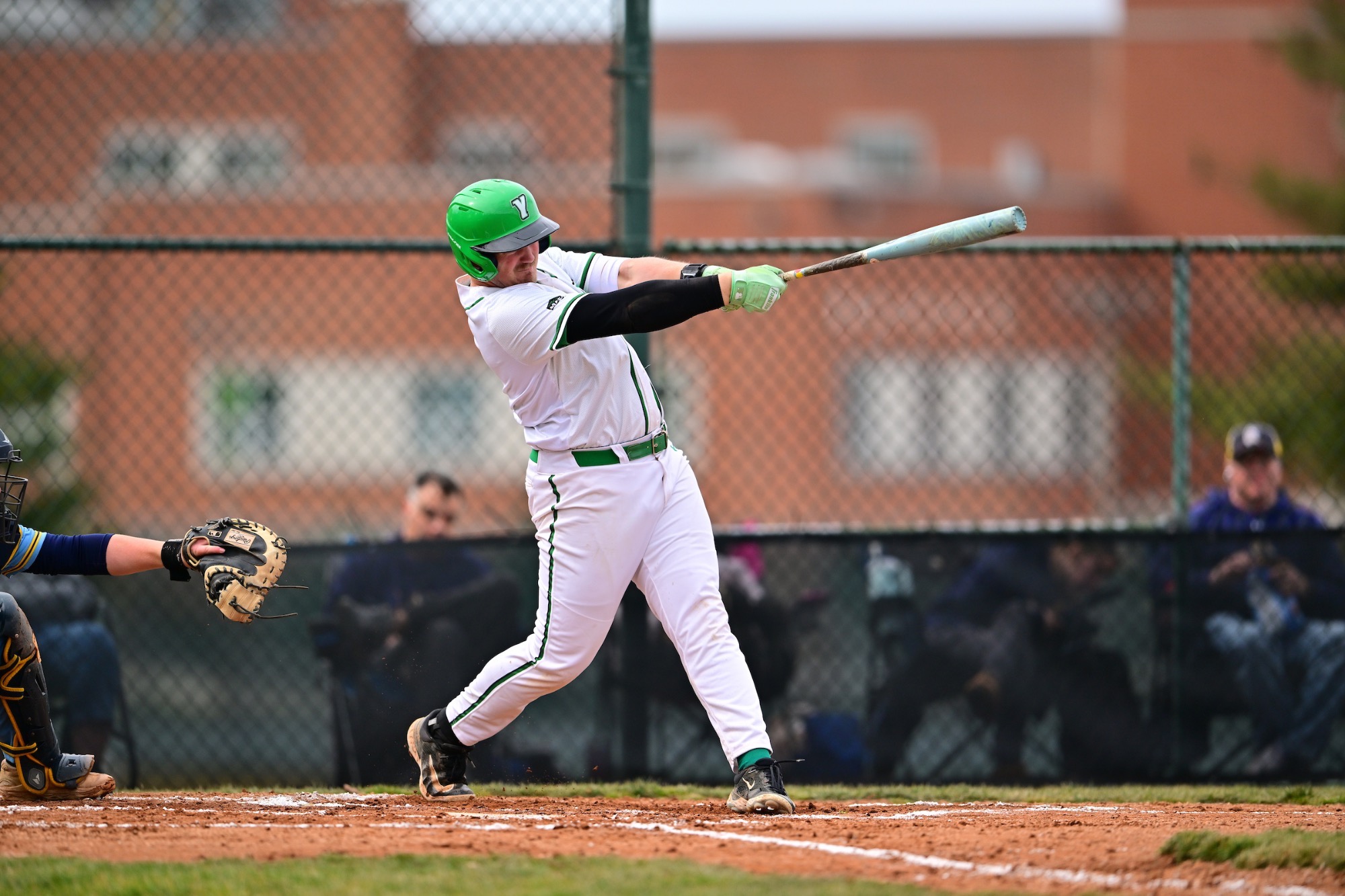 male in white uniform swinging baseball bat