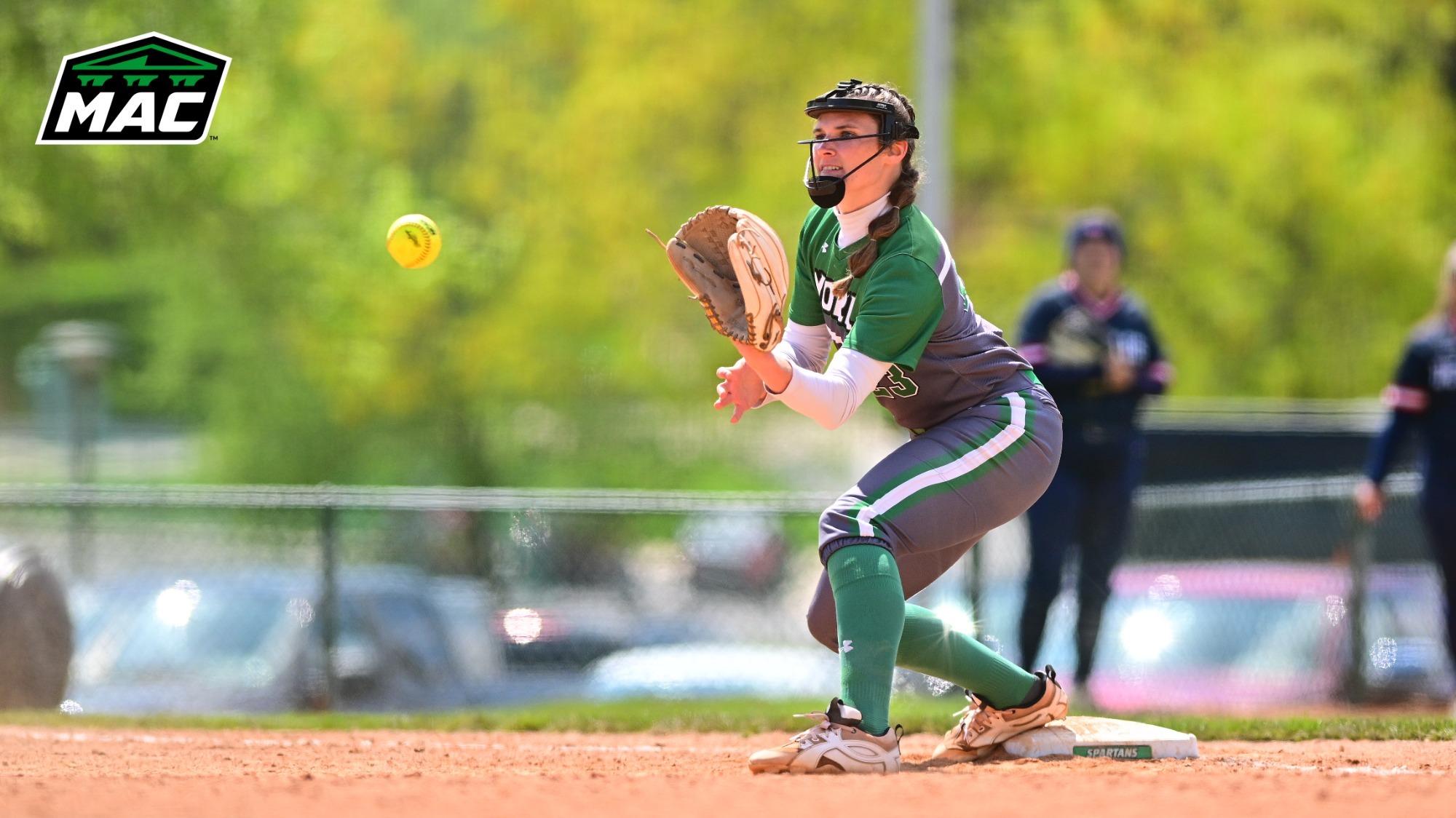 female softball player catches ball at first base