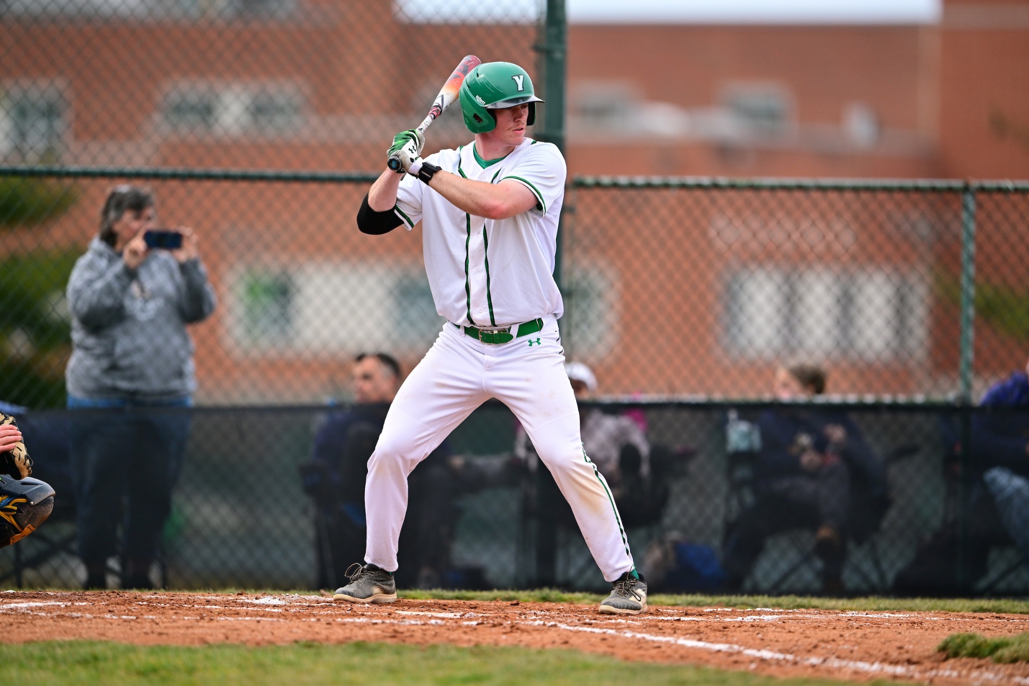 male in white uniform with baseball bat