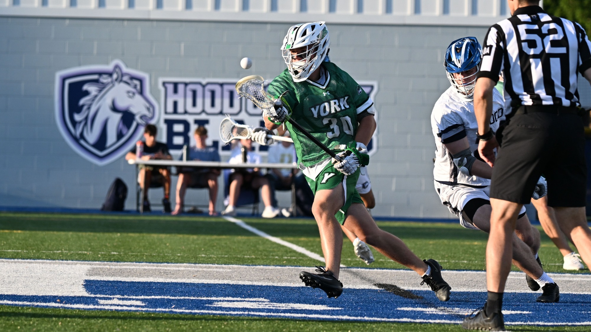 male lacrosse player in green jersey picks up a ground ball