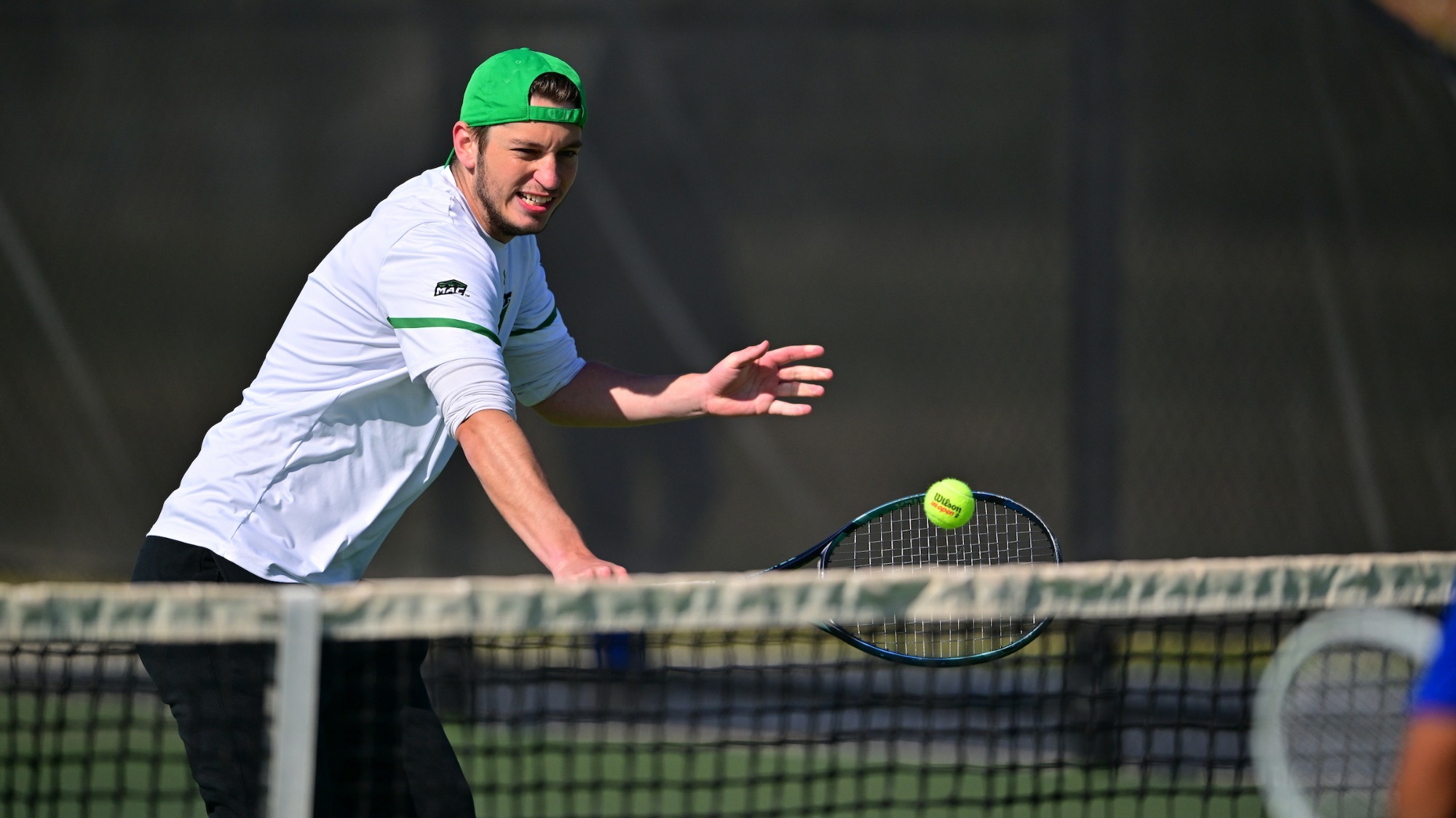 male tennis player back hand hits a shot