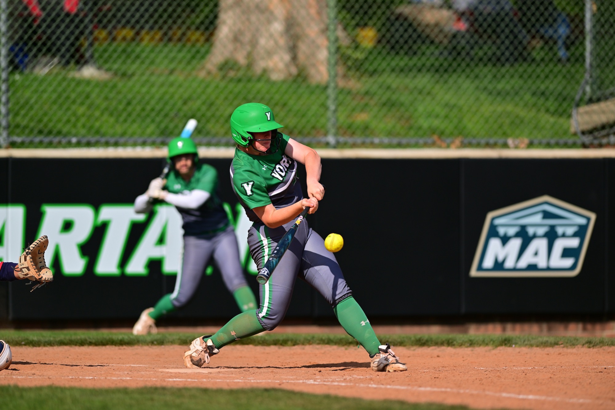 Female in grey uniform swinging softball bat