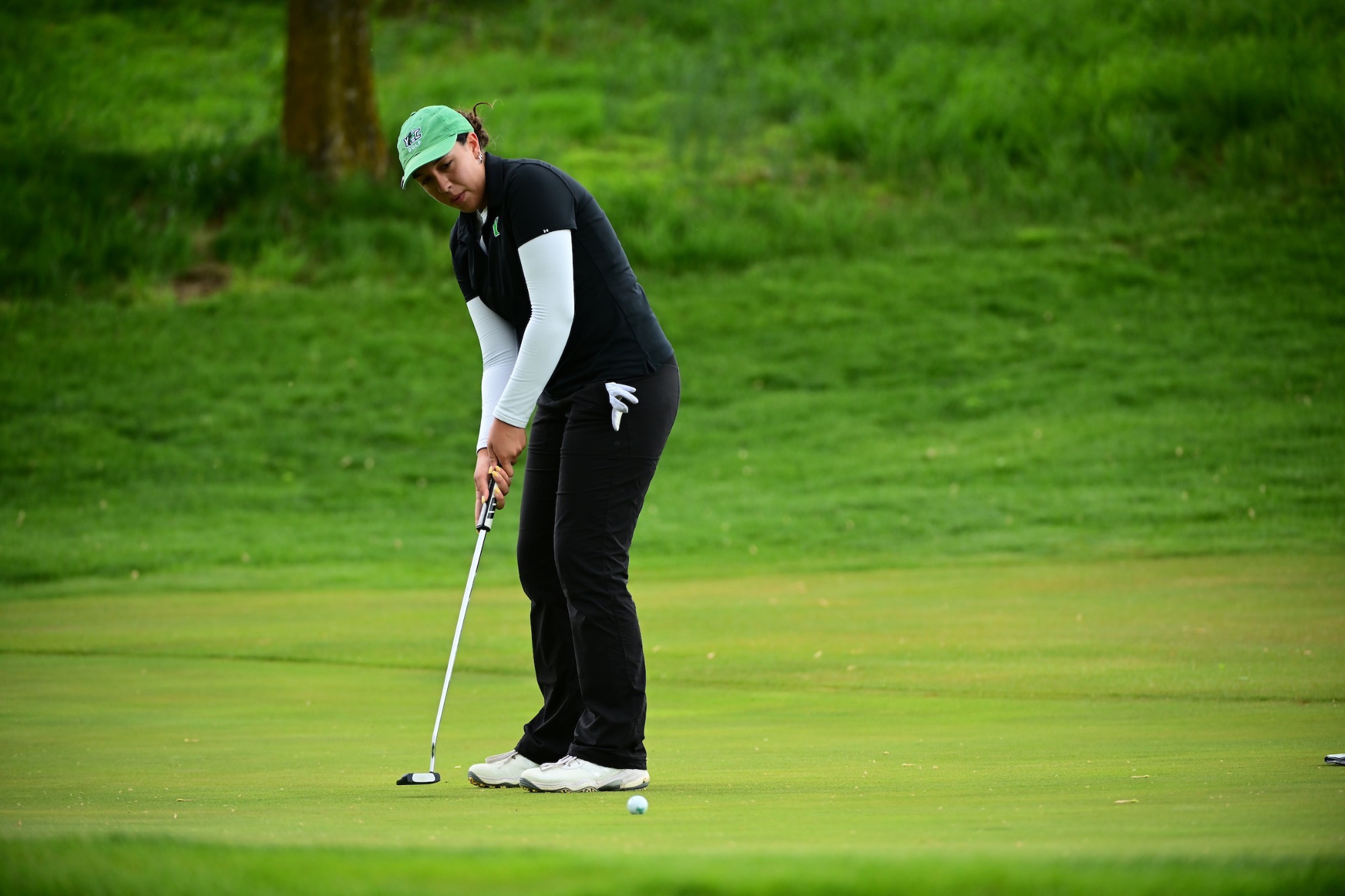 Female in black swinging golf club