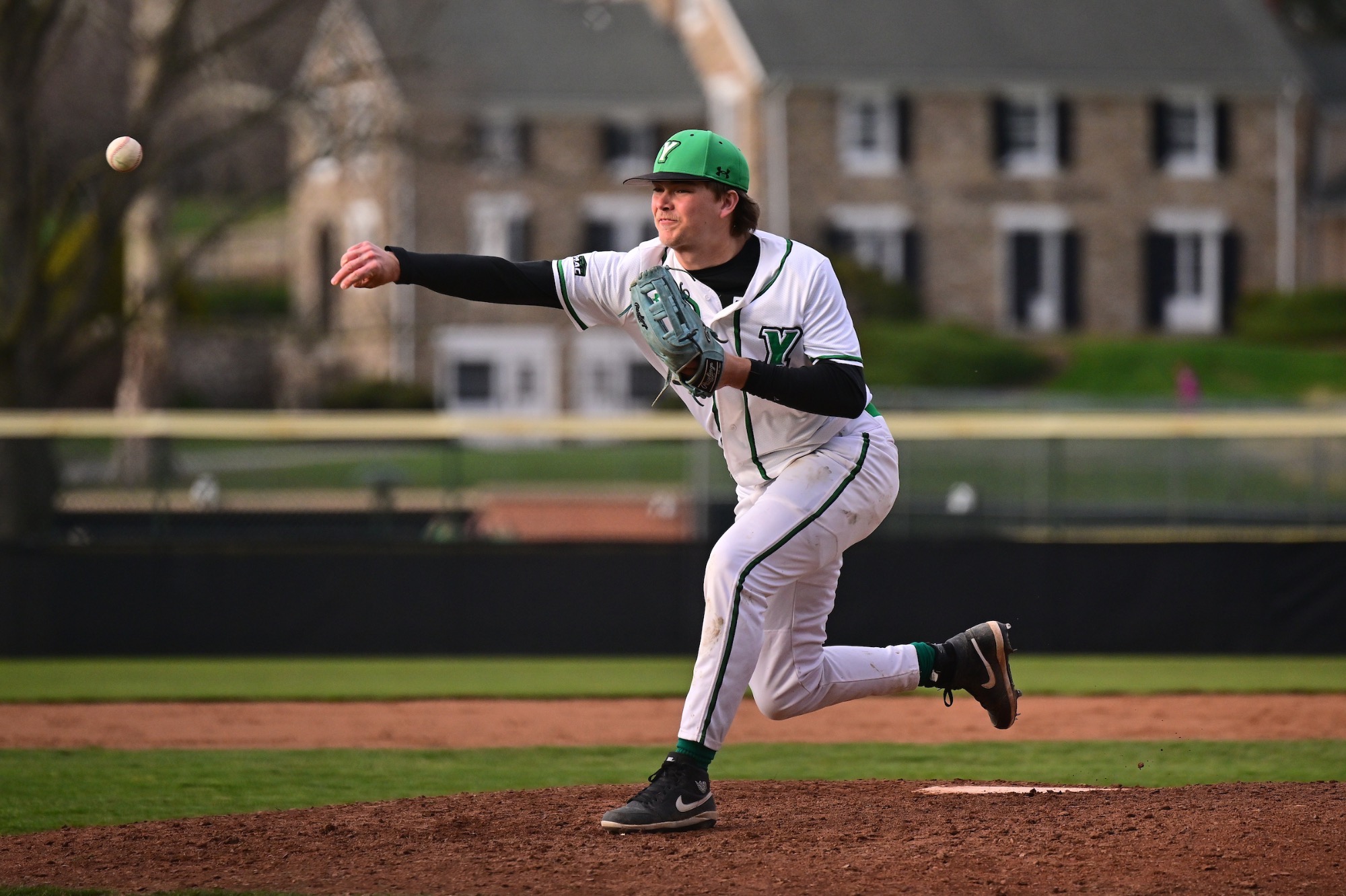 baseball pitcher in white uniform throwing a pitch 