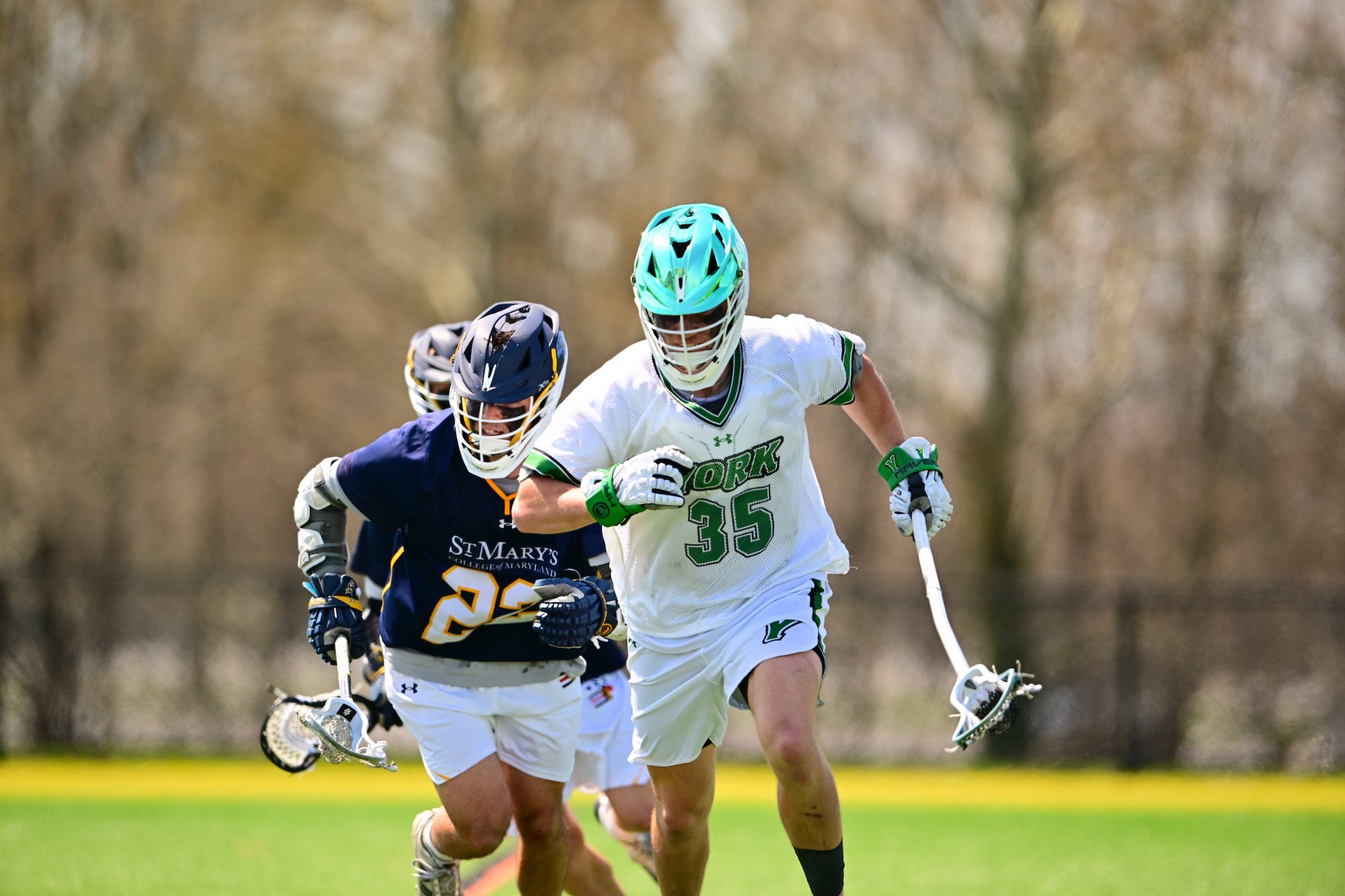 Male in white jersey running with lacrosse stick