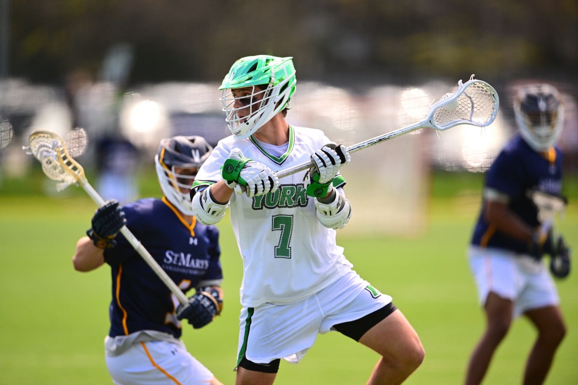male in white jersey holding lacrosse stick