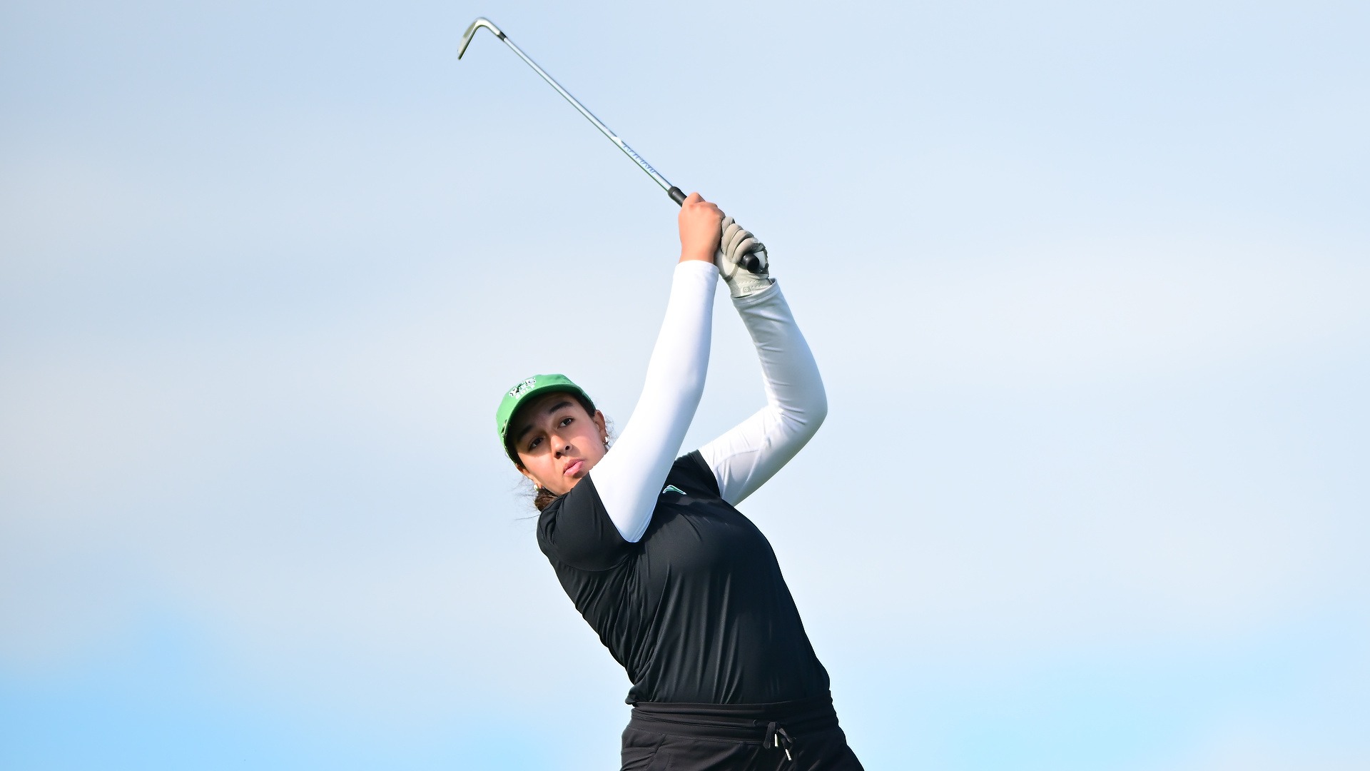 female golfer in black shirt swings club