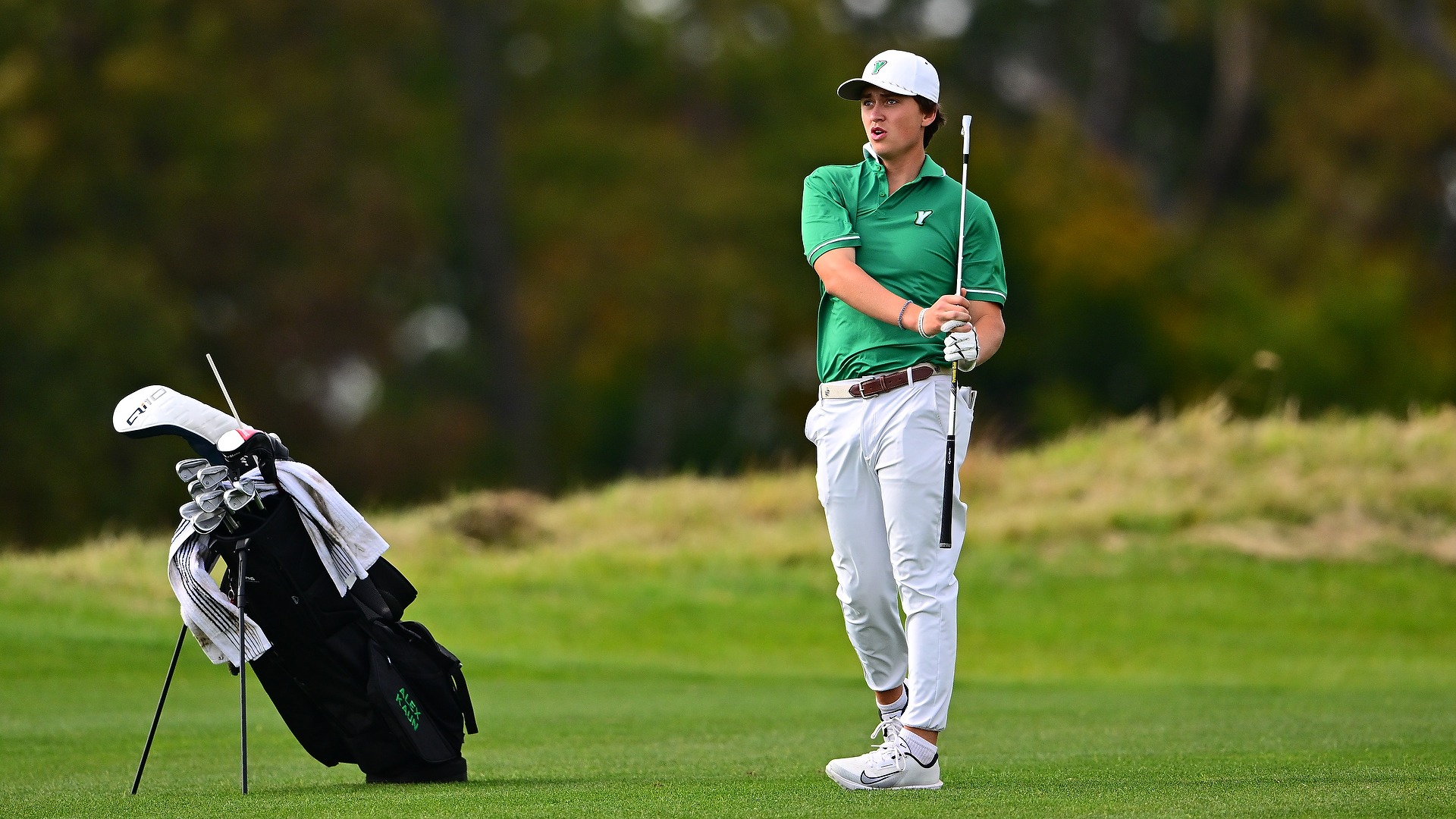 male golfer in green shirt holds club