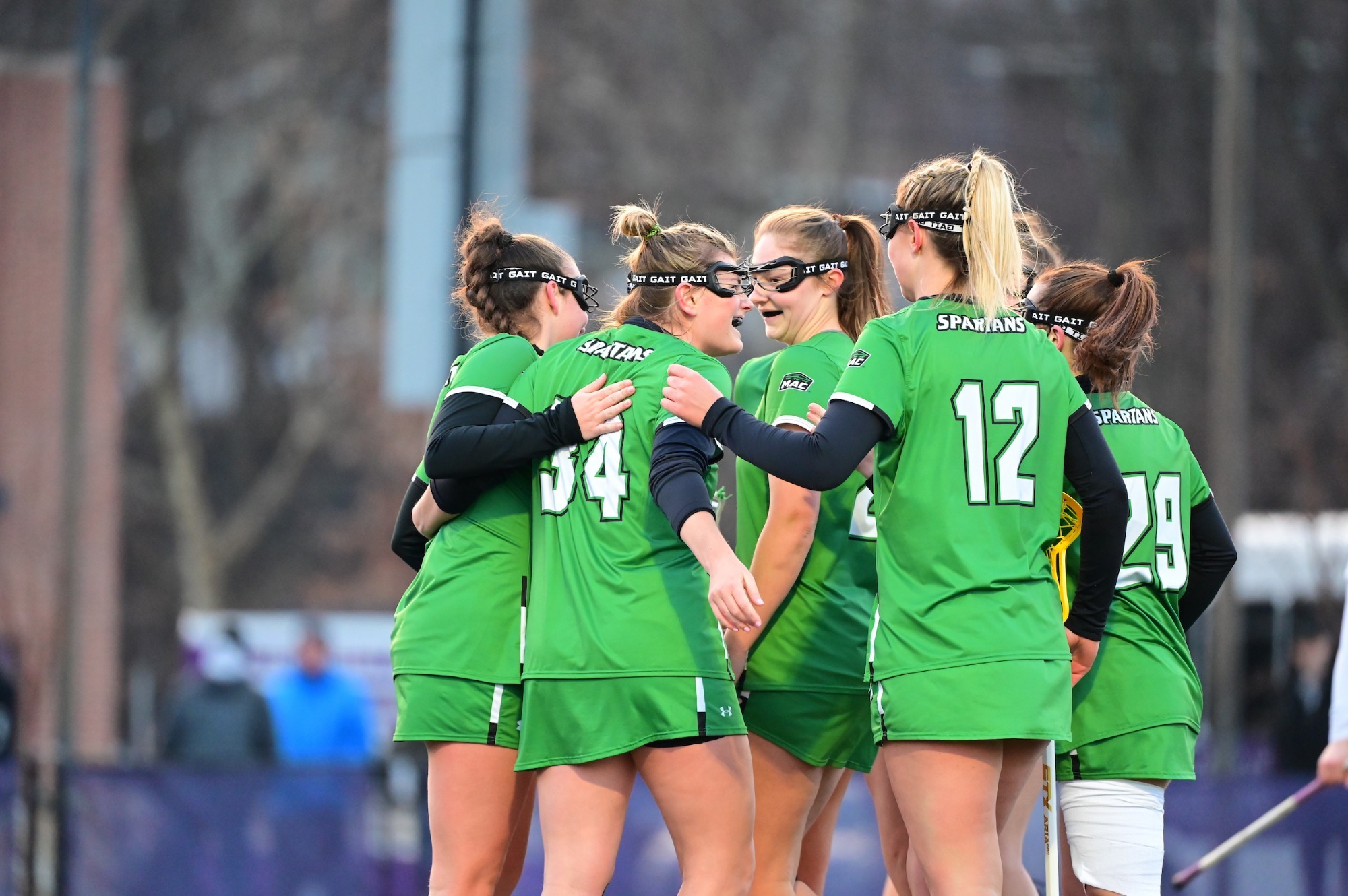 women's lacrosse team hugging after goal