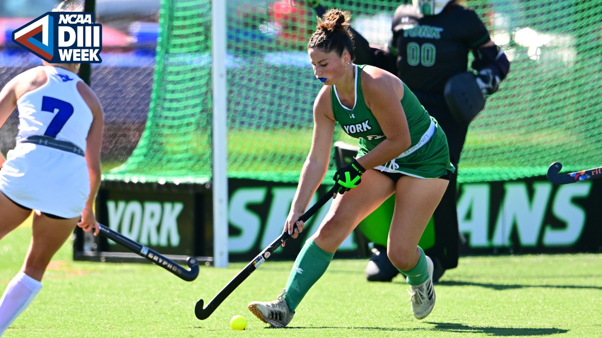 female field hockey player hits ball