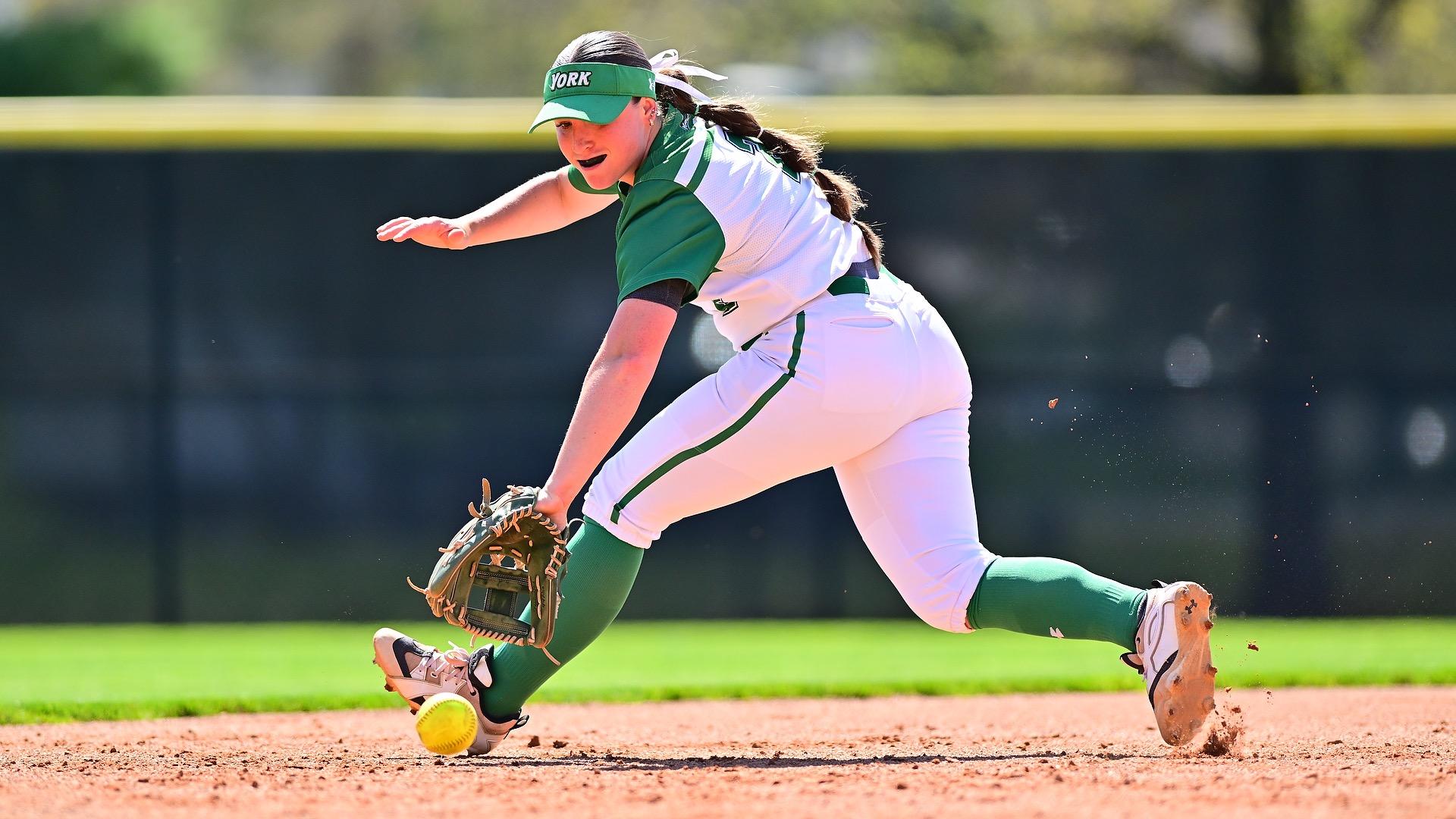 female in white uniform fielding softball