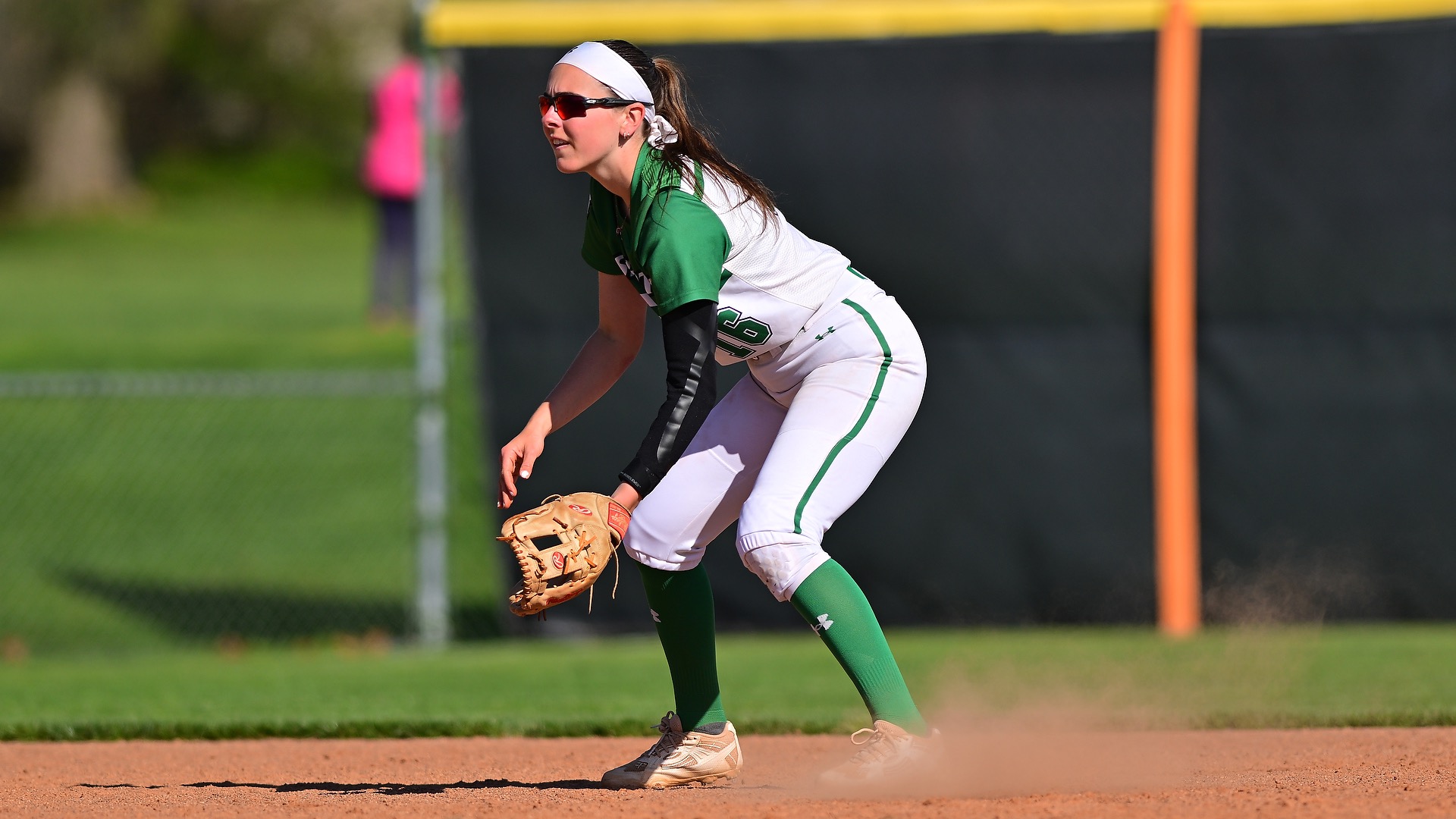 Female in white uniform fielding a ball