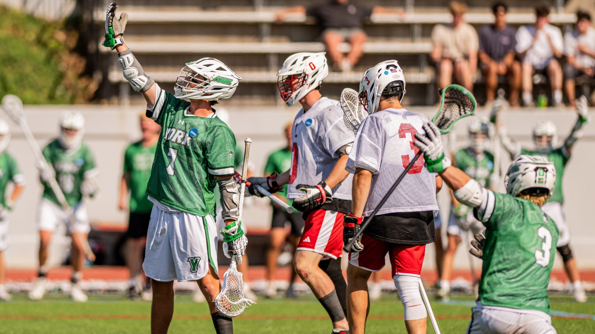 male lacrosse player celebrates goal in front of opponents