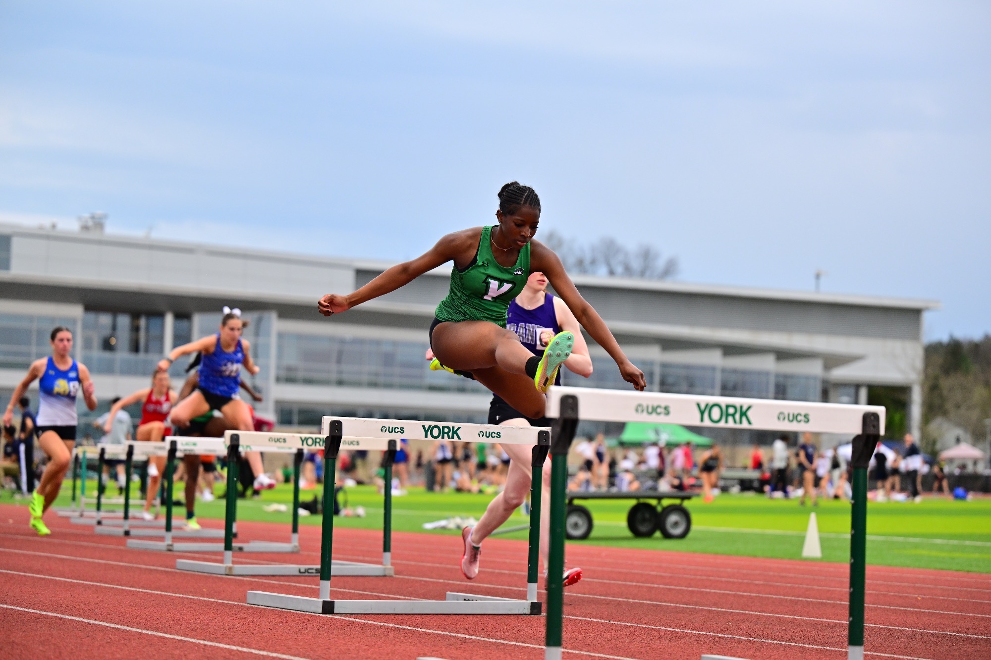 female in green jumping hurdle