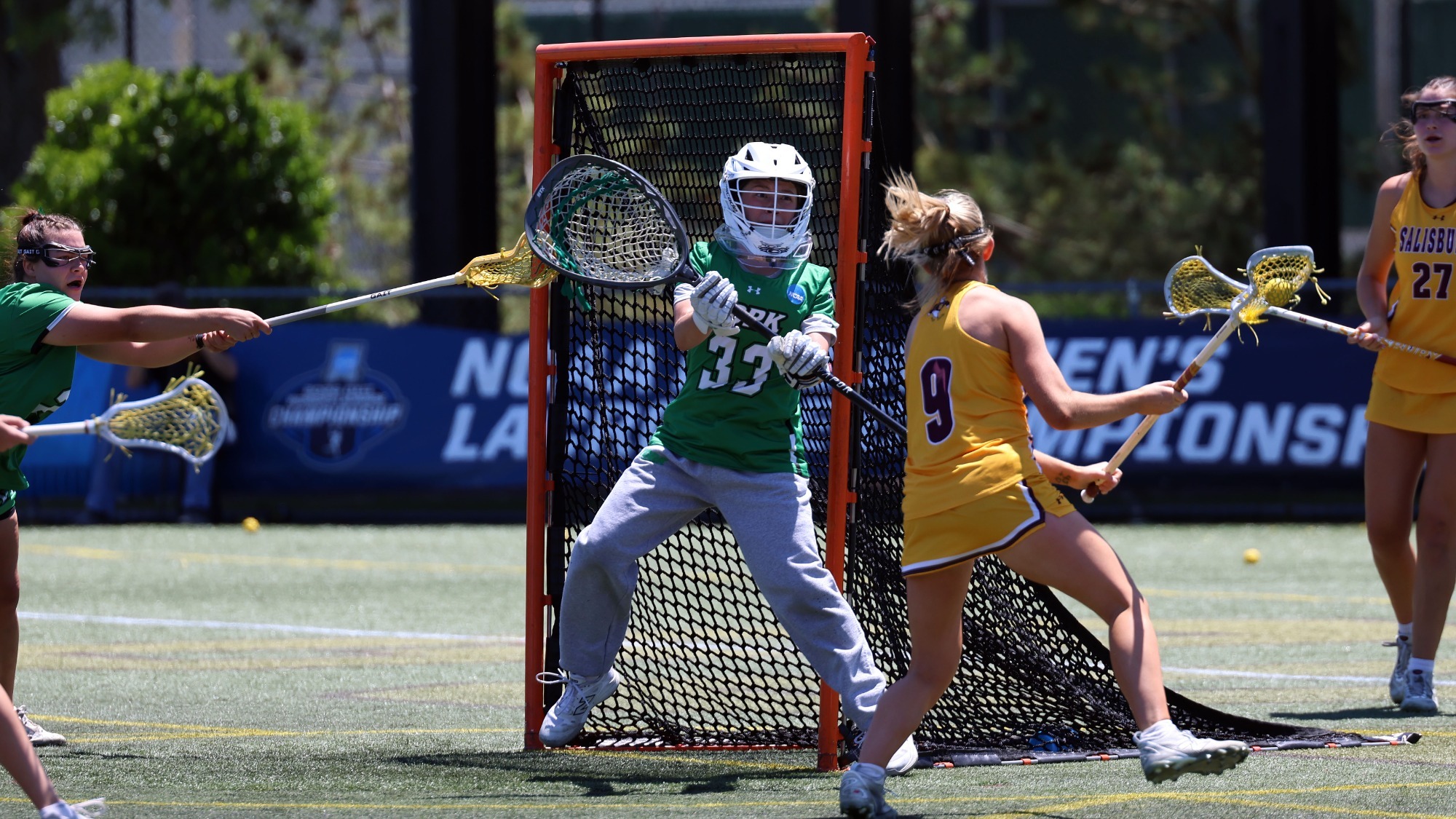 women's lacrosse goalie eyes attacker in anticipation of shot