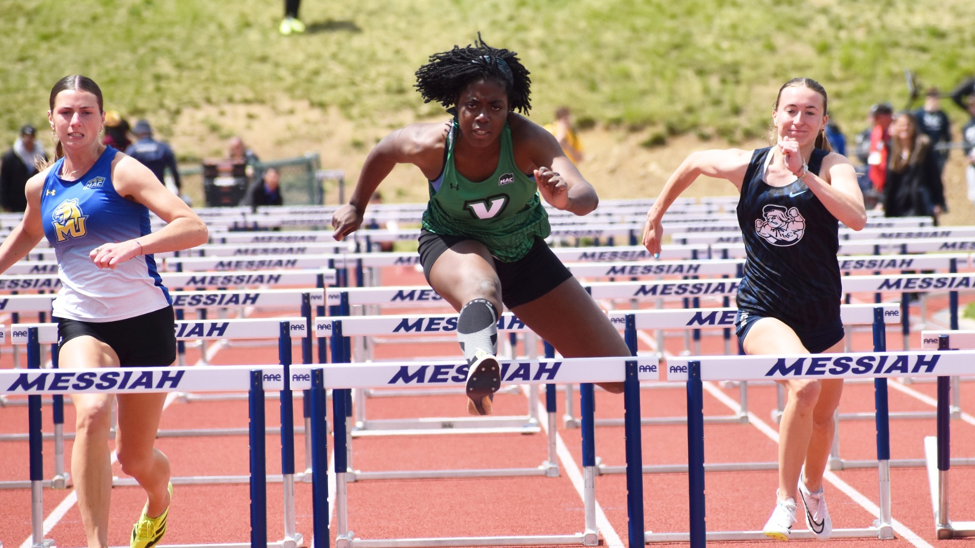 female track athlete leaps over hurdle