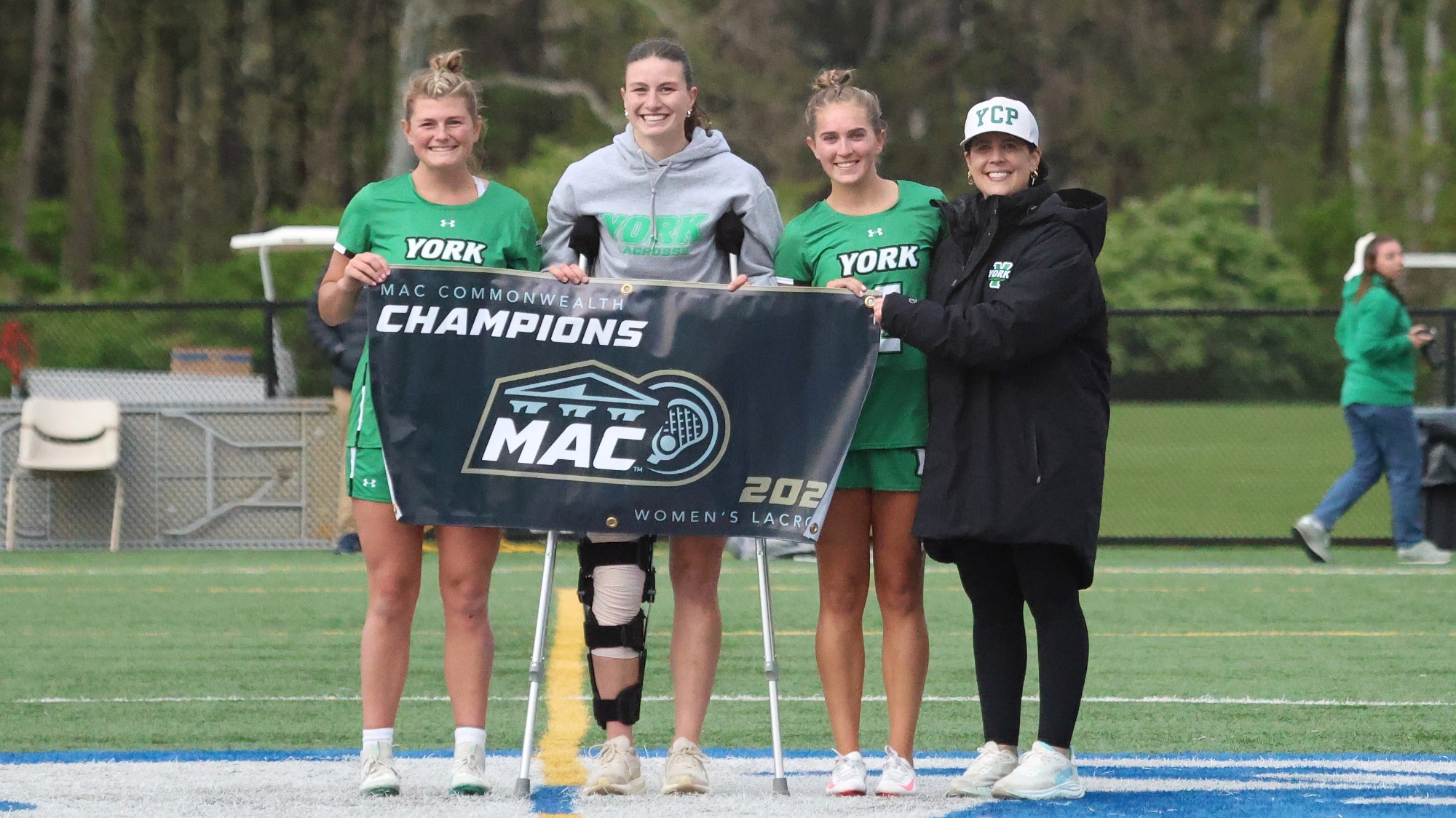 women's lacrosse captains pose for picture with championship banner