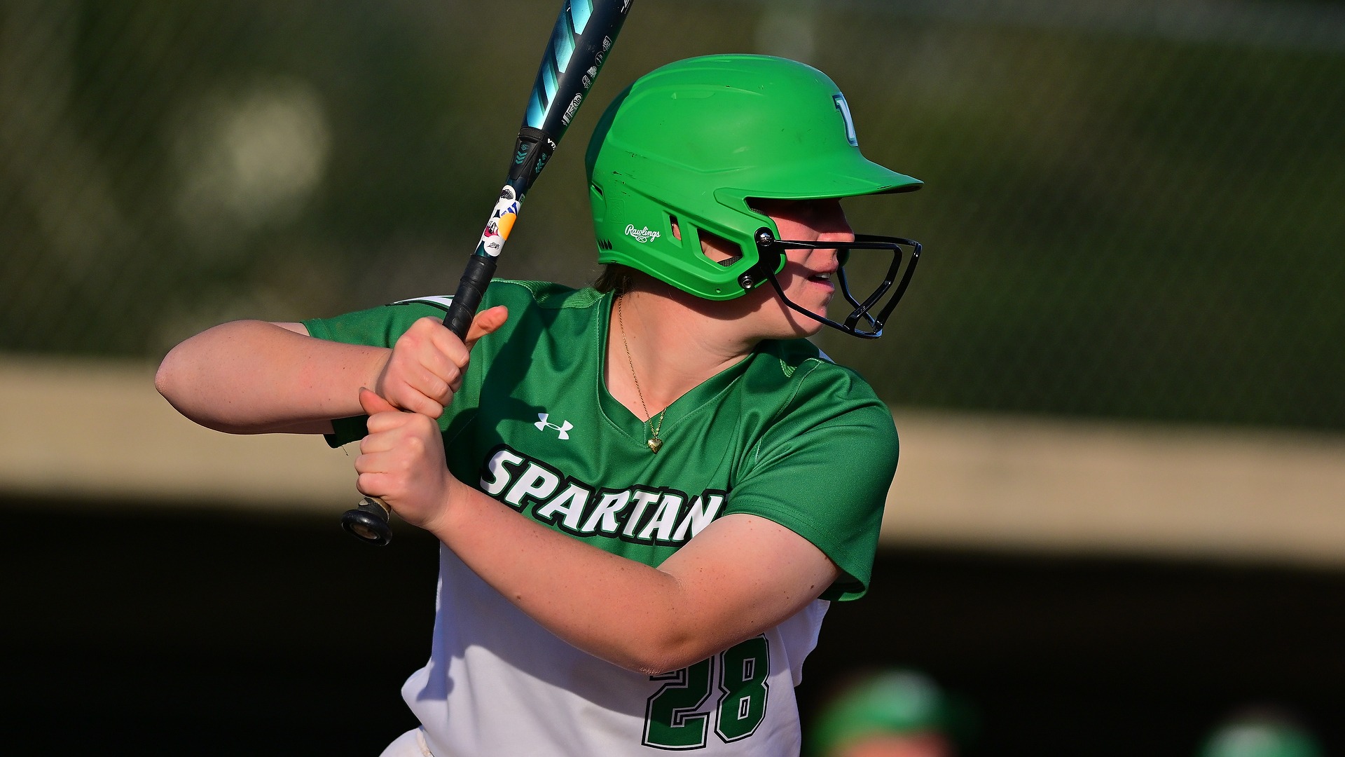 softball batter in green jersey waits for a pitch