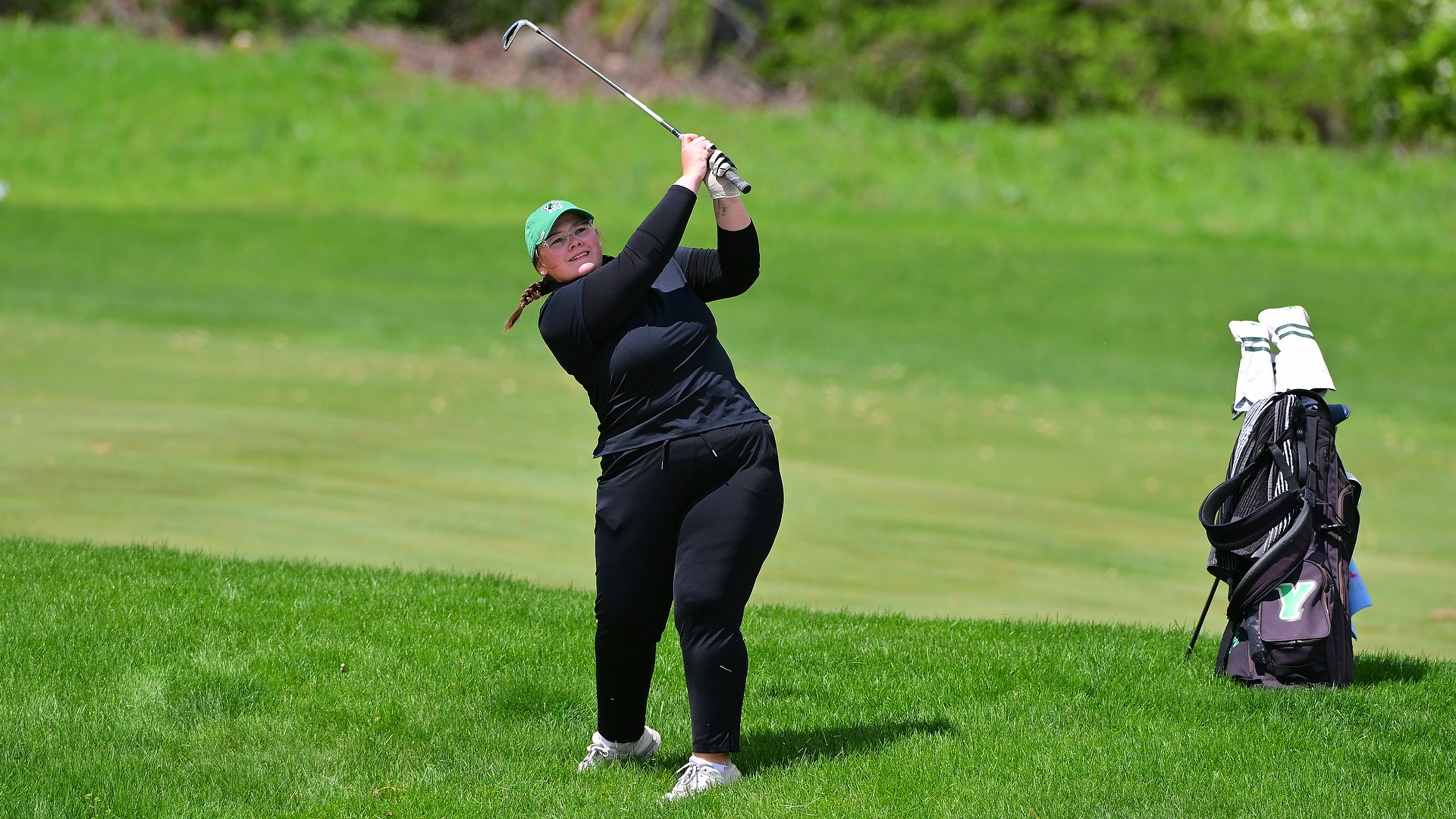 female golfer tracks a wedge shot from the rough