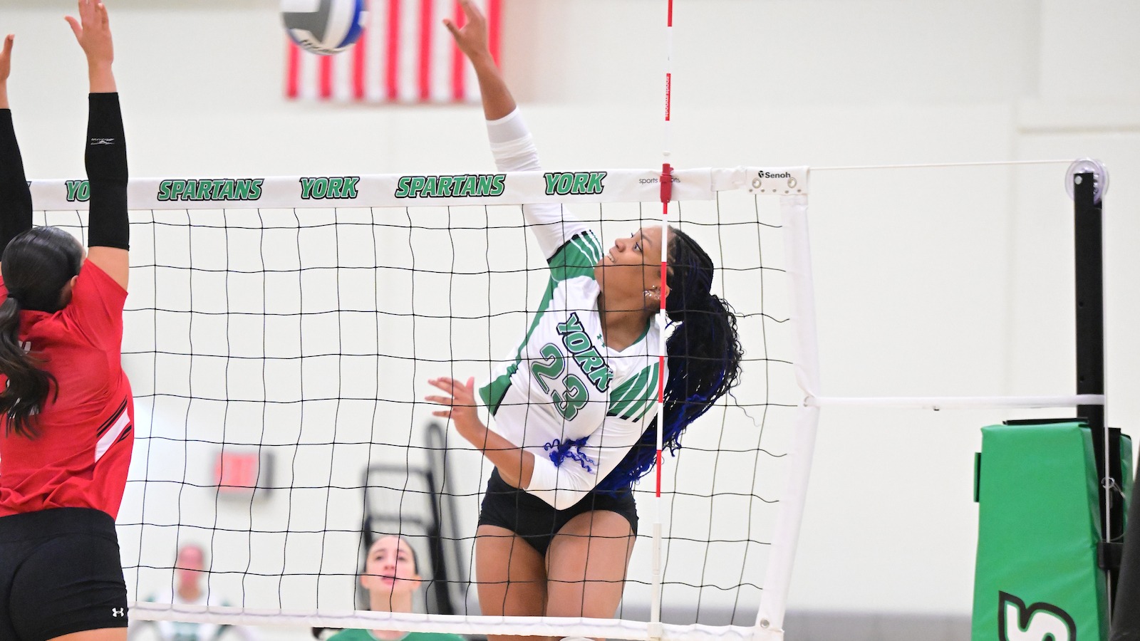 female volleyball player spikes ball over net