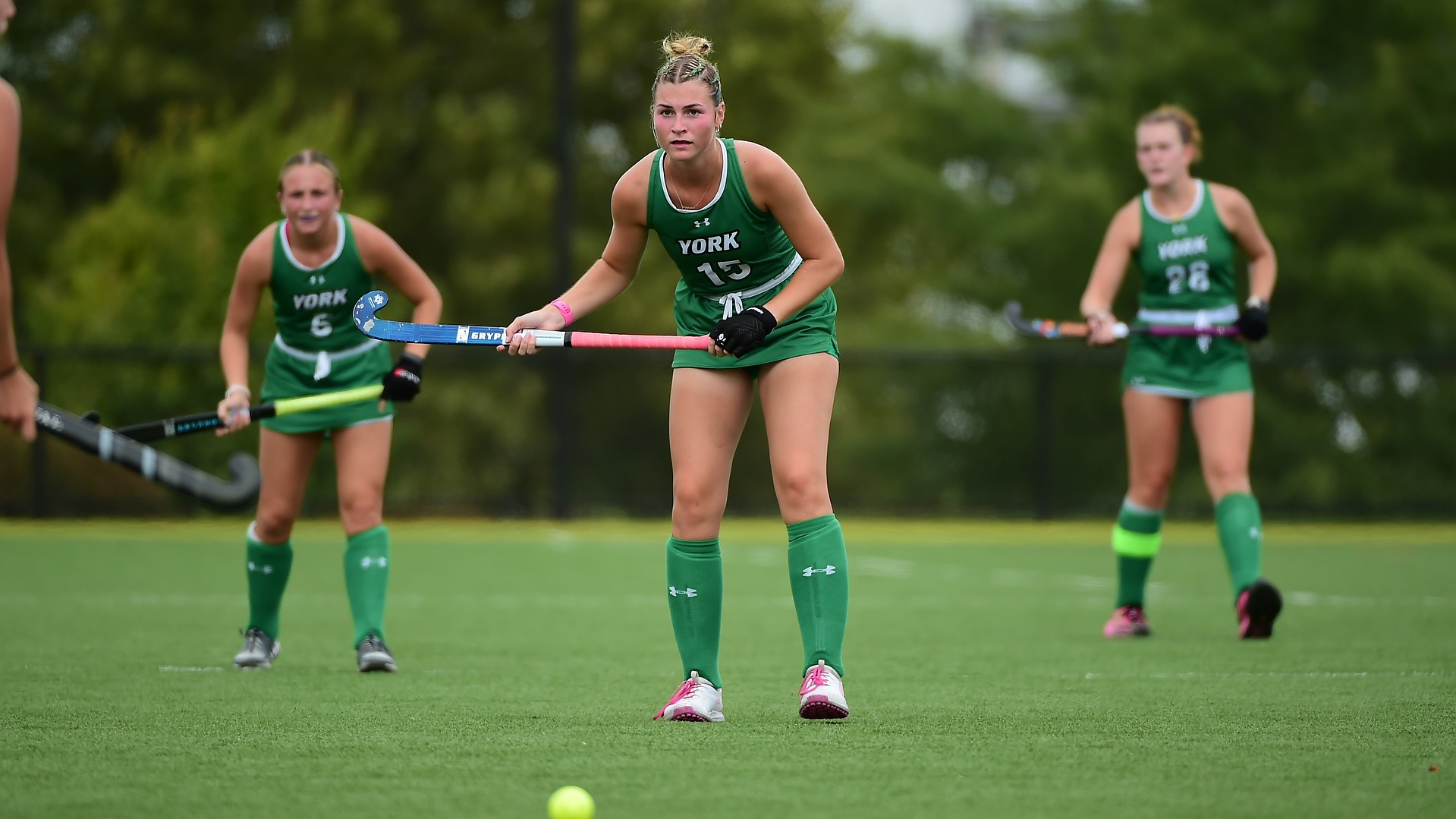 Female in green uniform with field hockey stick