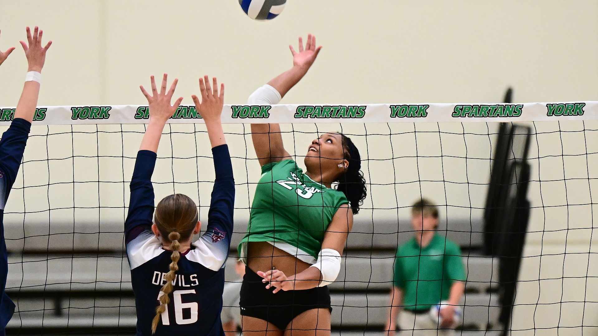 female volleyball player spikes ball over net