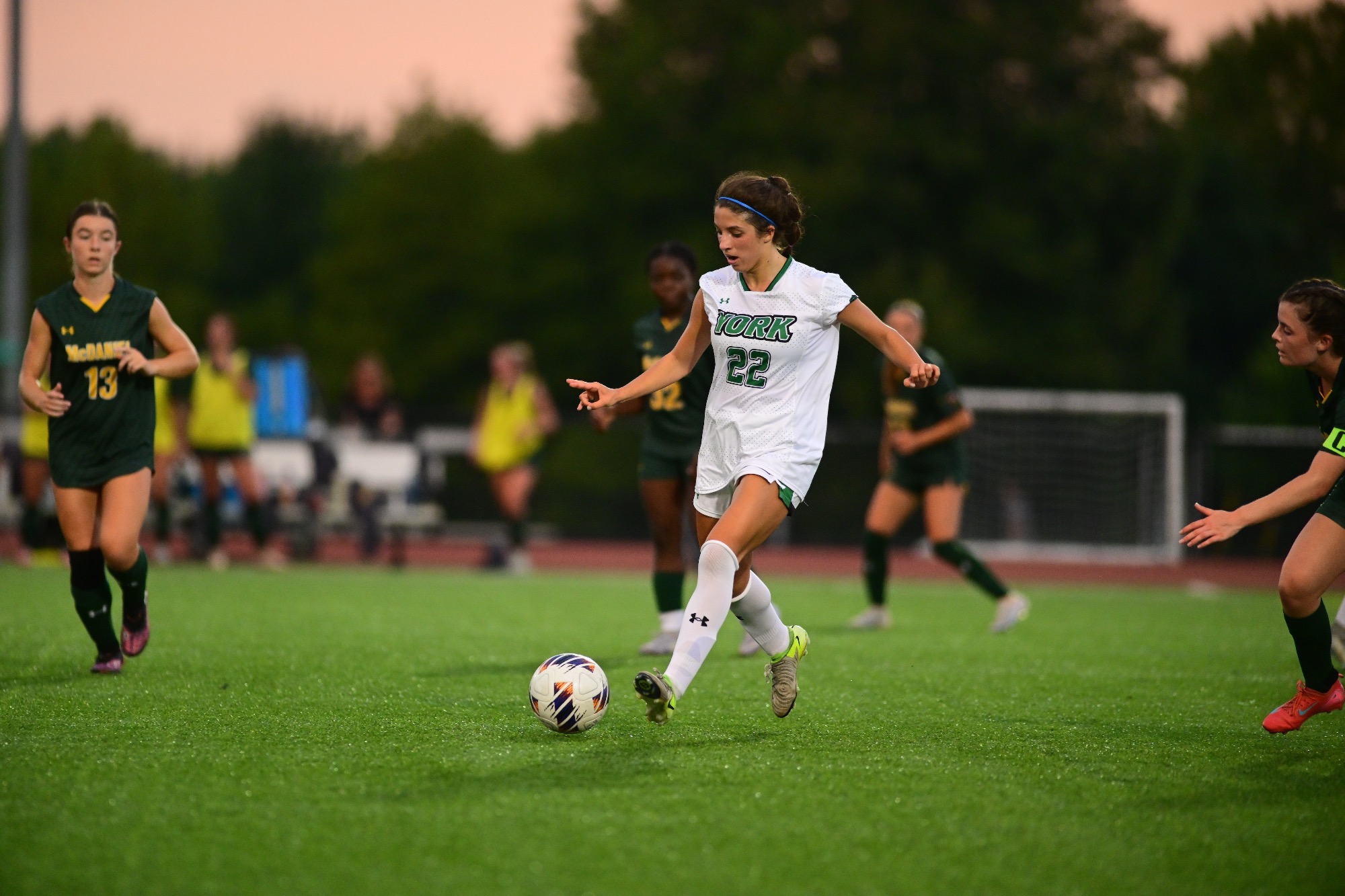 Female in white soccer uniform kicking ball