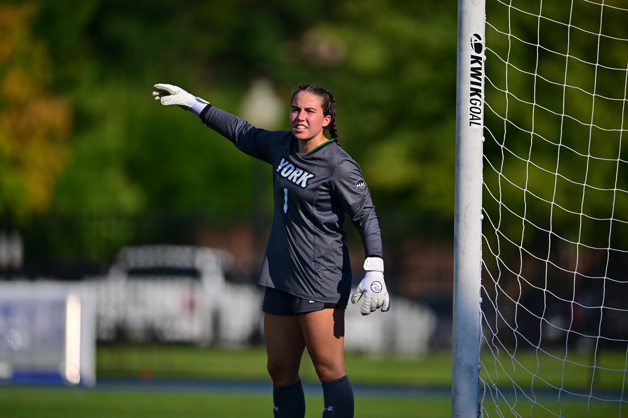 Female in soccer goal pointing