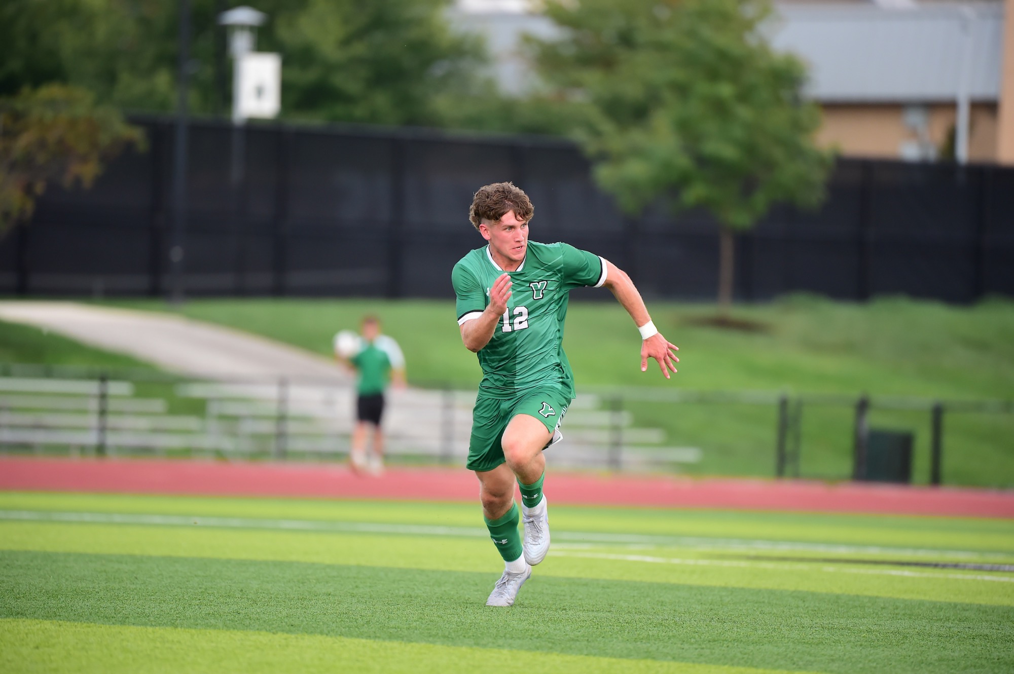 Male in green uniform running for soccer ball