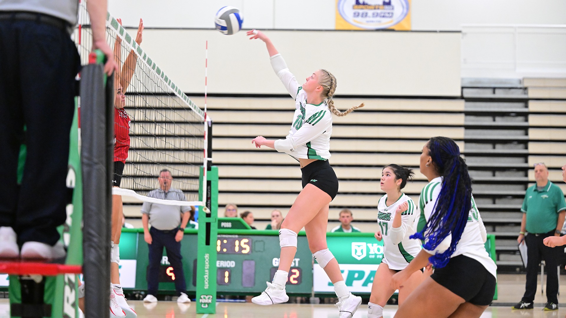 female volleyball player hits ball over the net