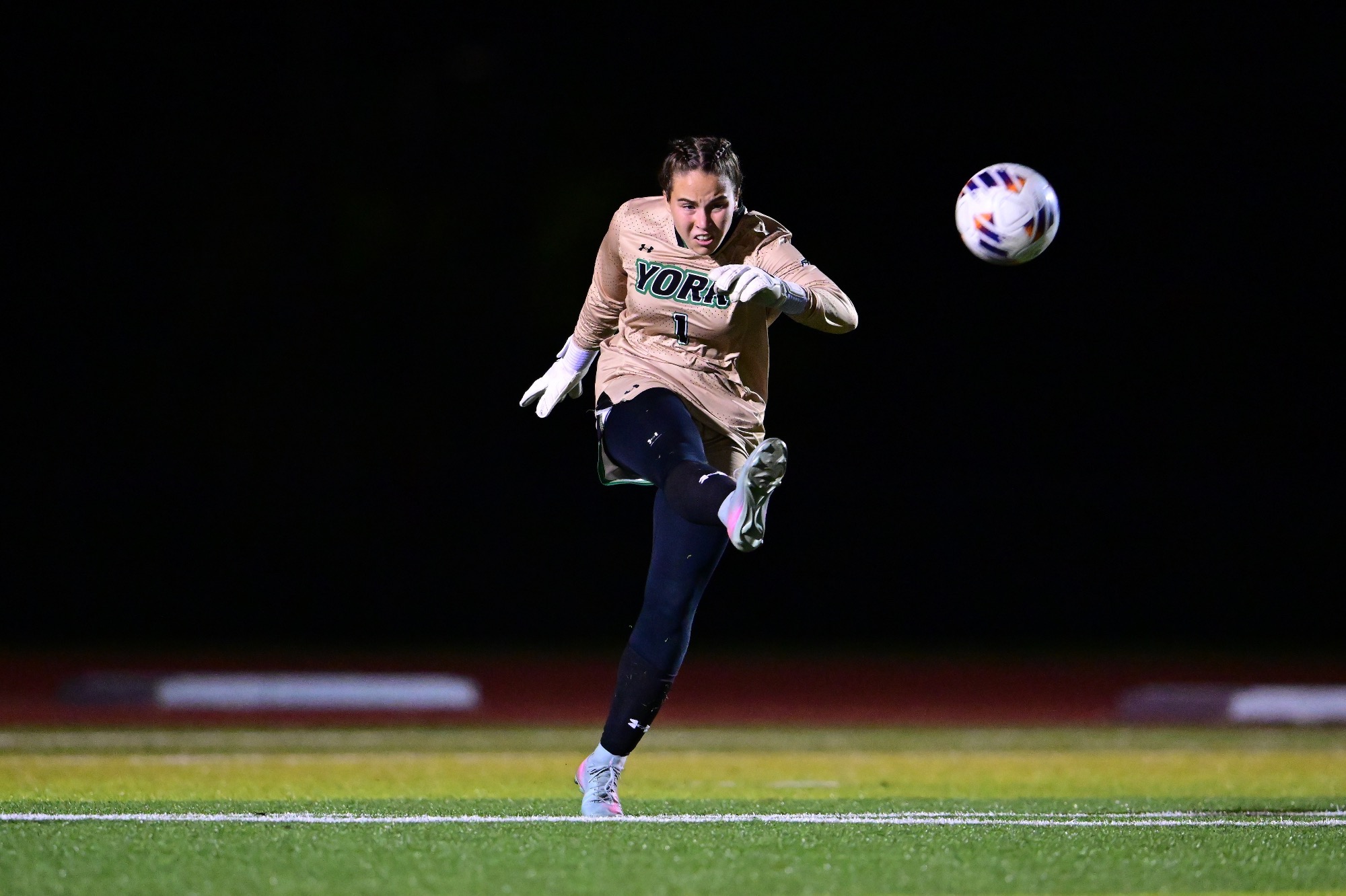 Female in goalie kit punting soccer ball