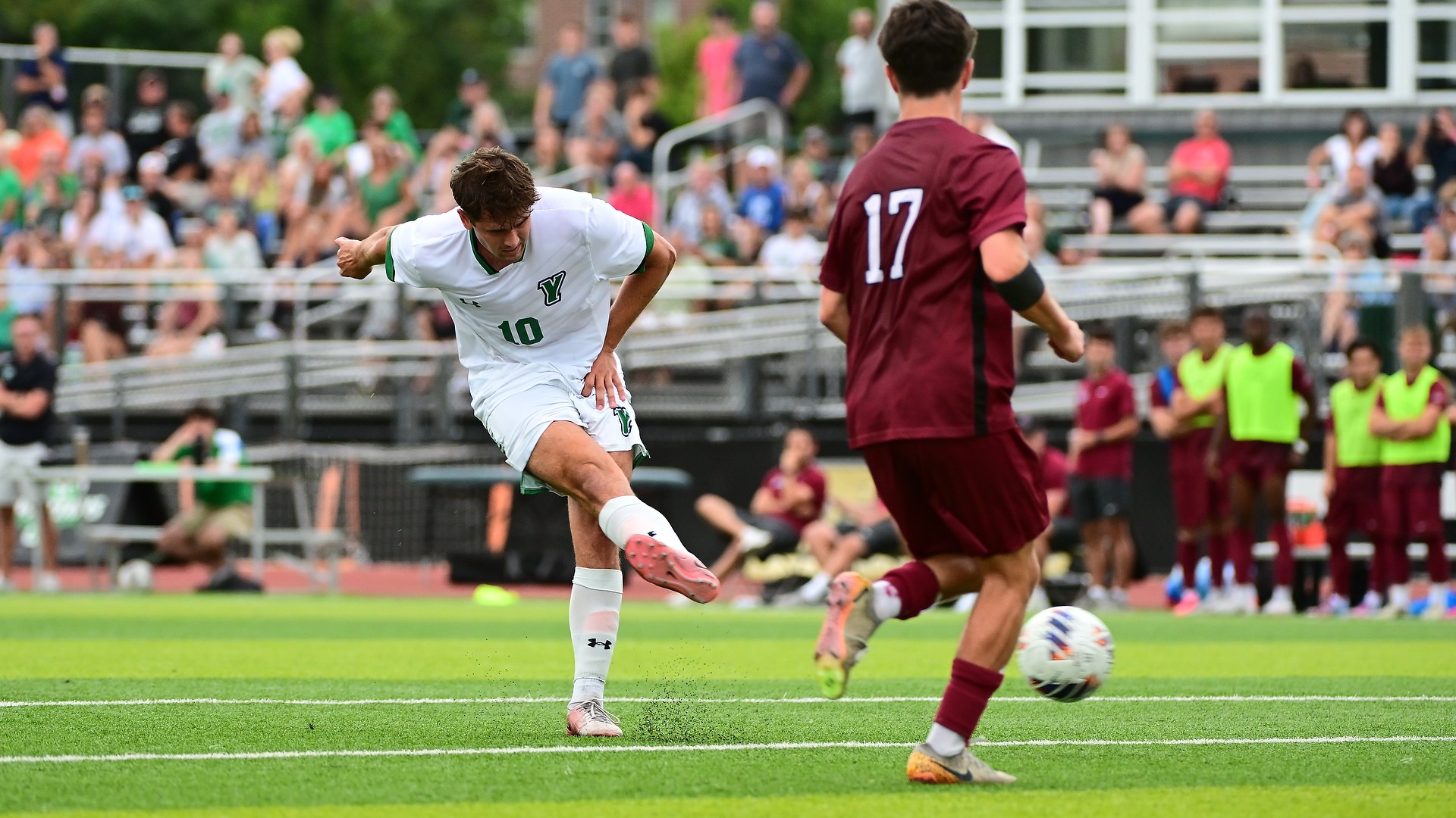 men's soccer player follows through after shooting ball