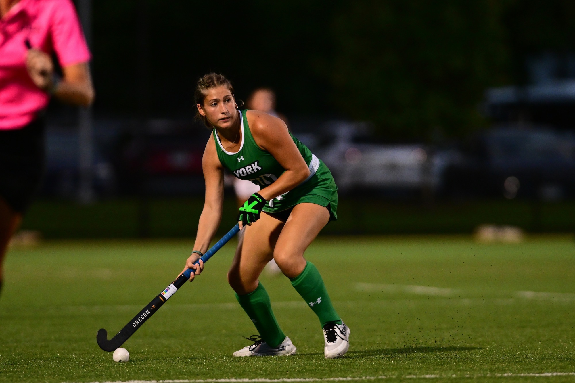 Female in green uniform with field hockey stick