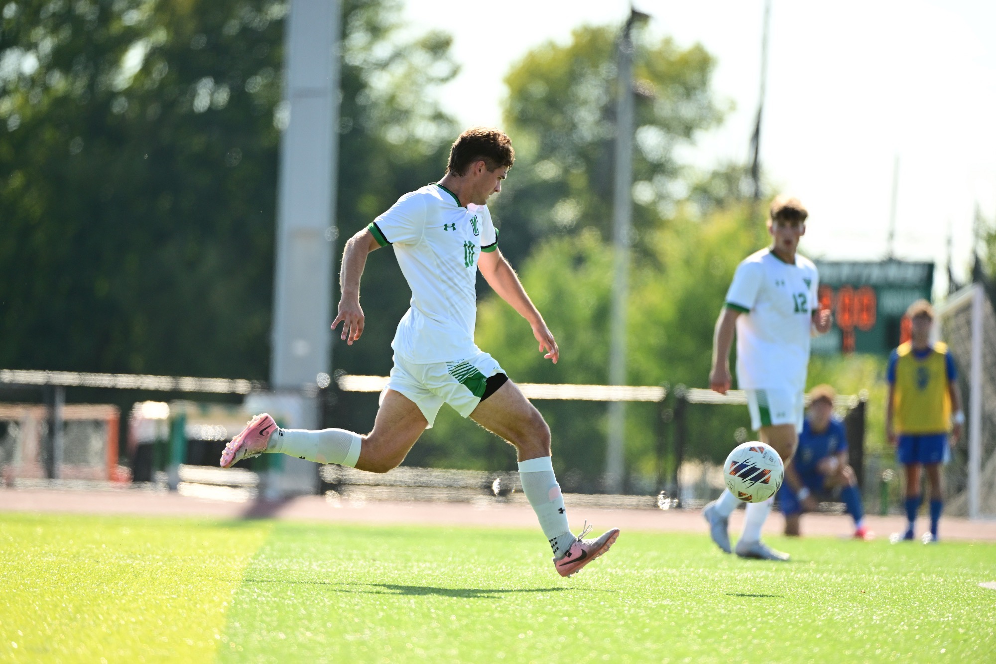 male in white uniform dribbling soccer ball