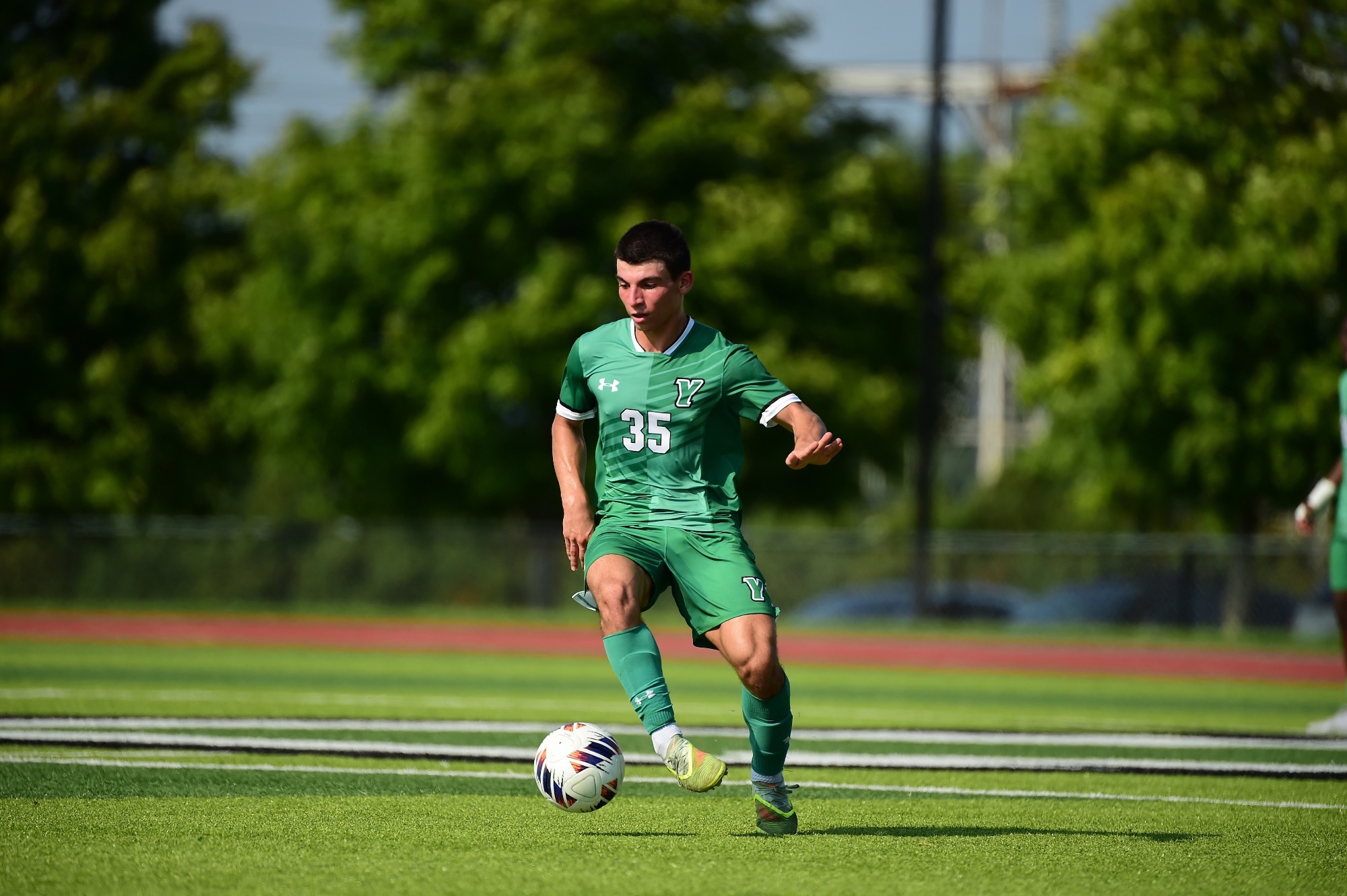 Male in green uniform dribbling soccer ball